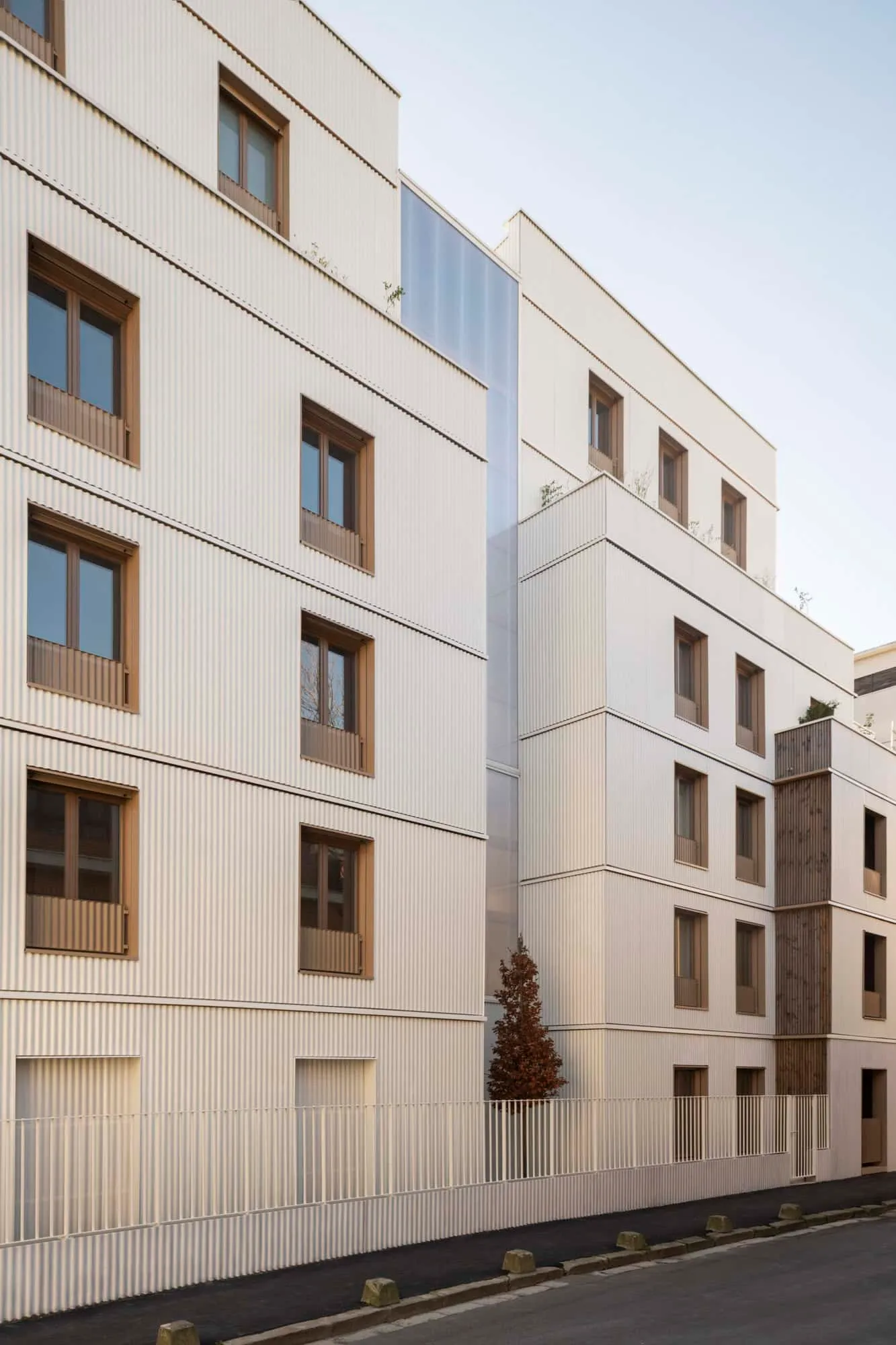 Angled view of the stepped white and timber façade with recessed windows