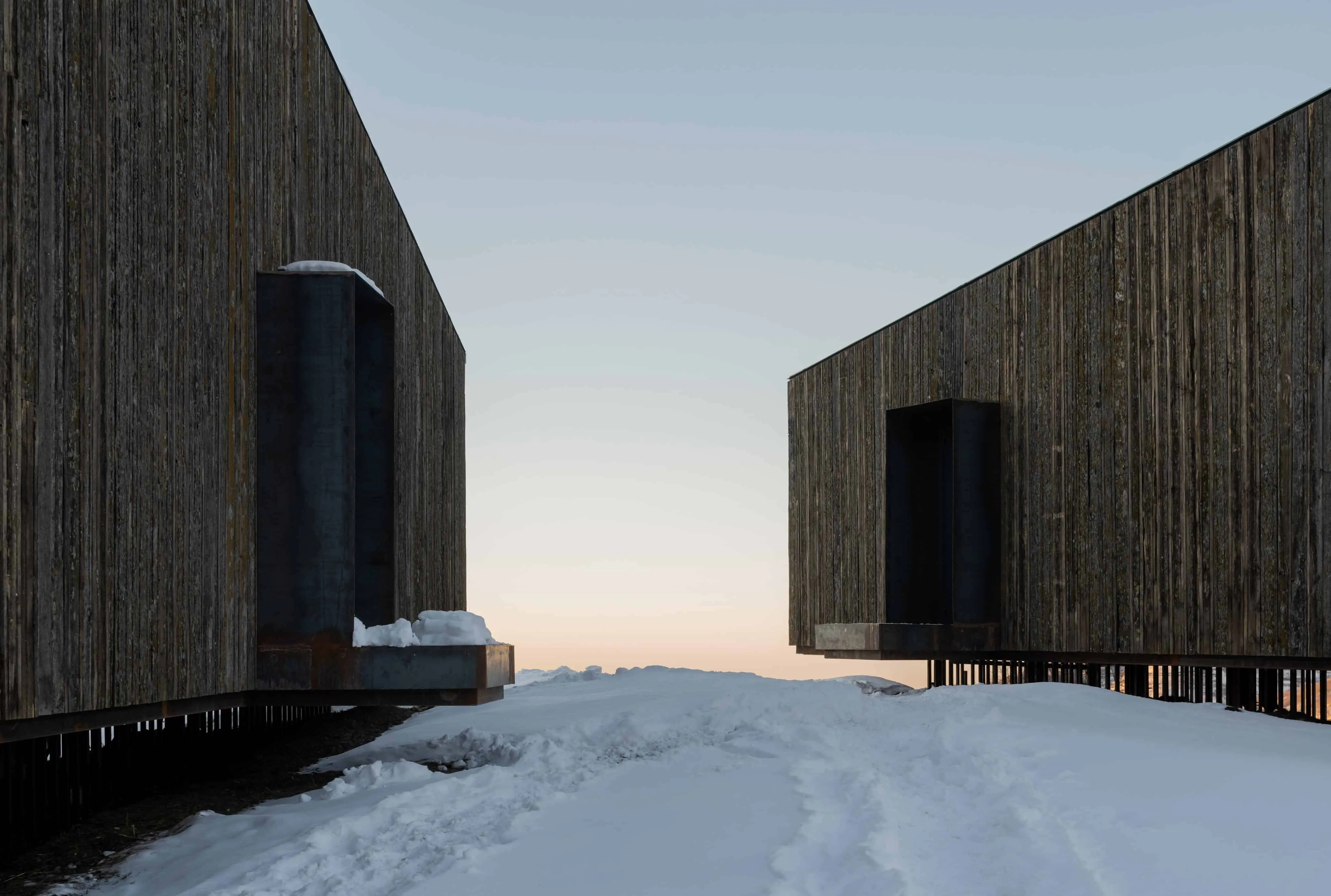 两间阿姆小屋相对而立，中间有雪道，日落时分拍摄。