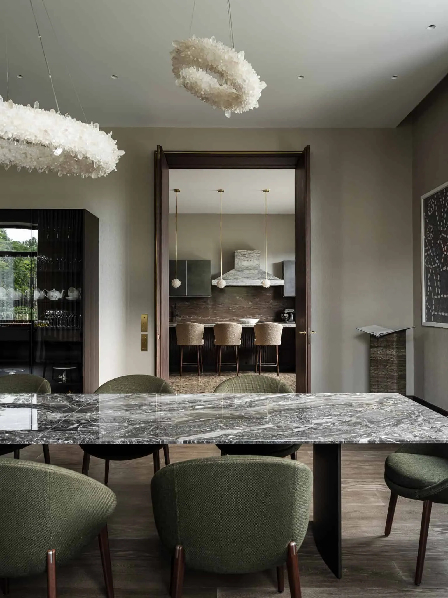 Їдальня з зеленими стільцями, що відкривається на сучасну кухню.