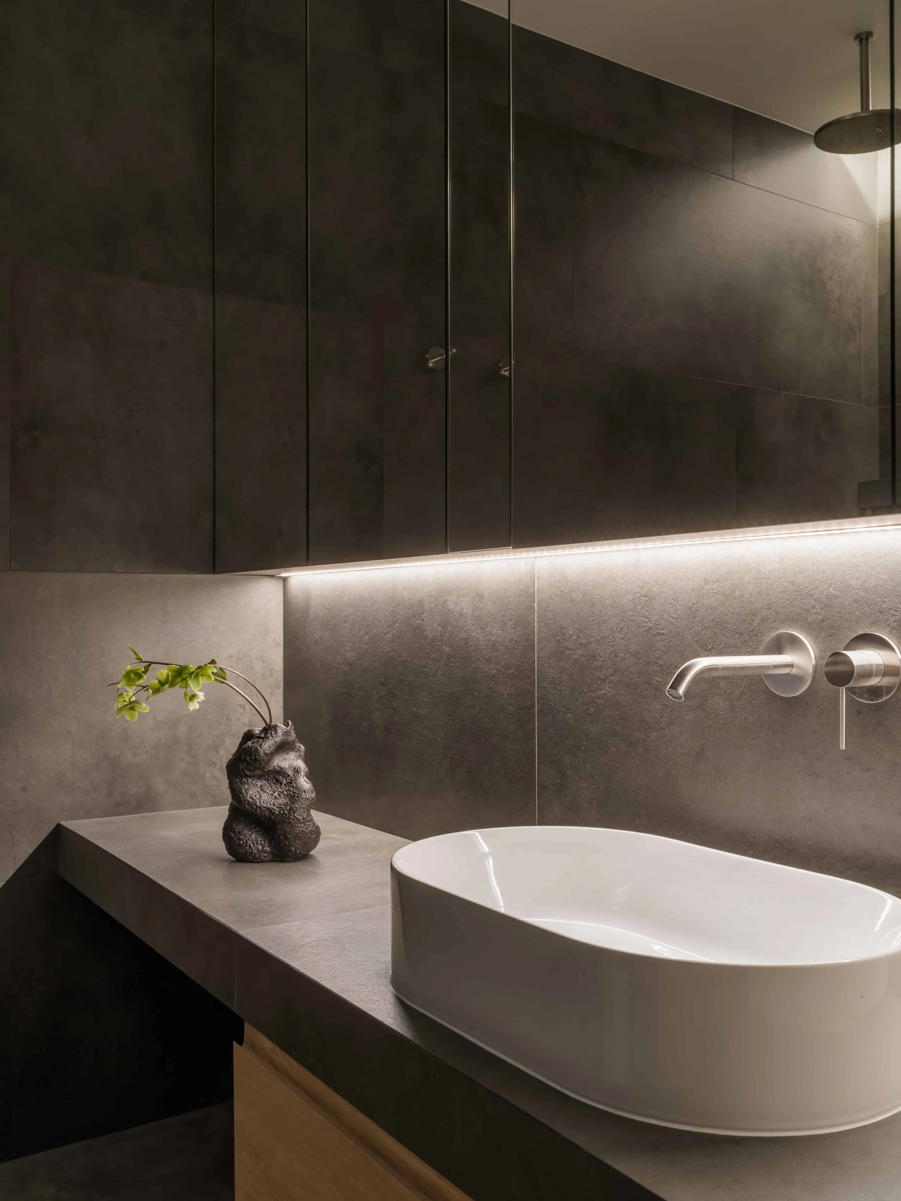 白色洗手台配深色石材台面，柔和照明。