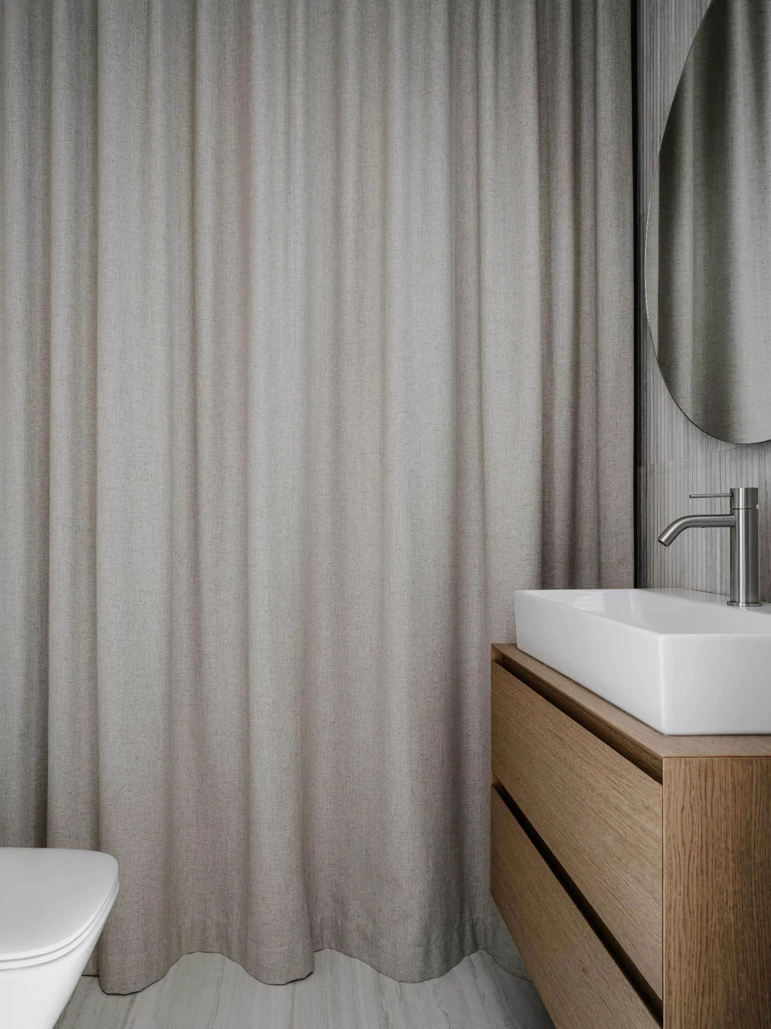 Minimalist bathroom with curtains and wooden sink.