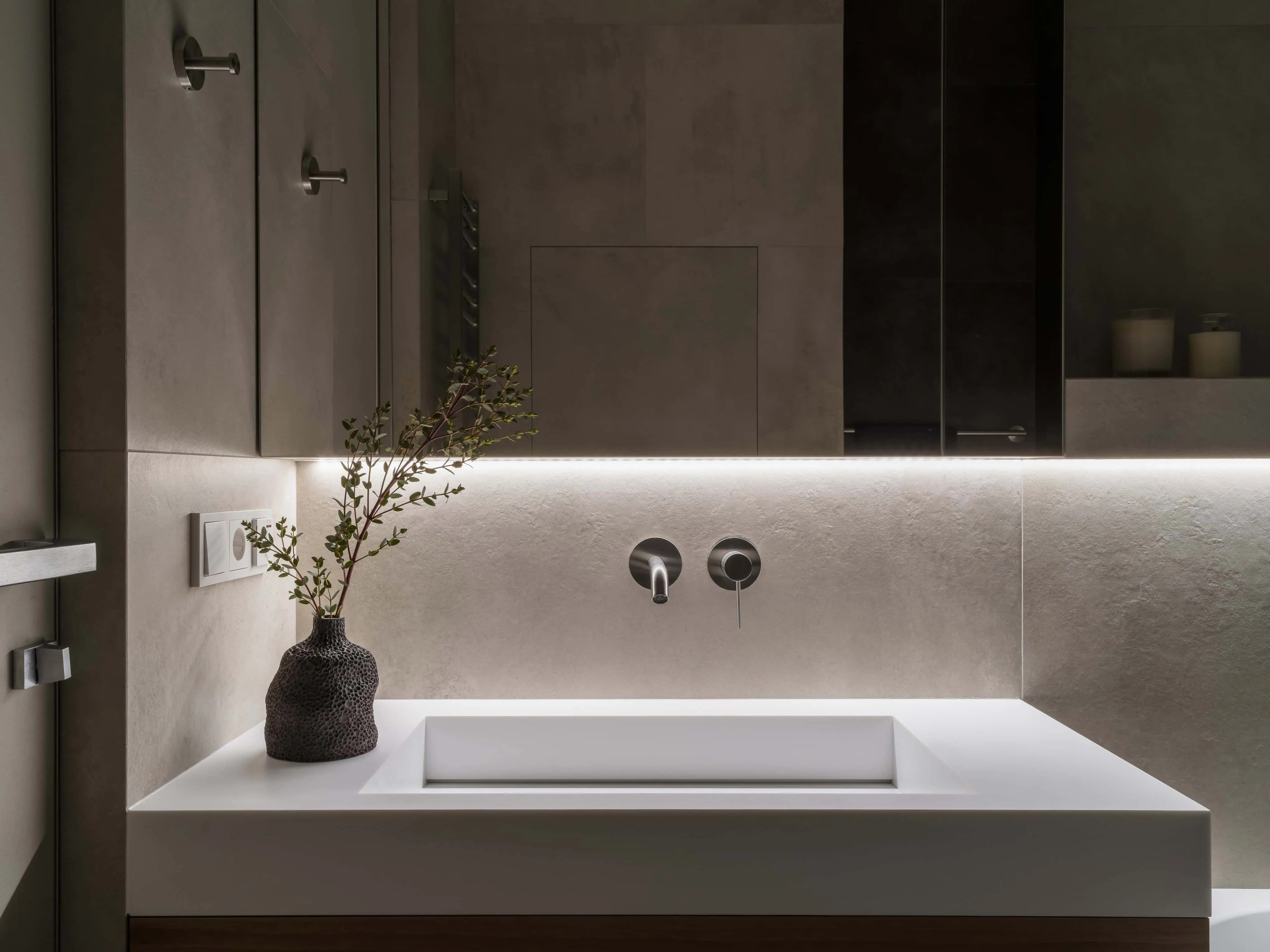 现代矩形洗手台，集成照明与纹理陶瓷装饰特写。