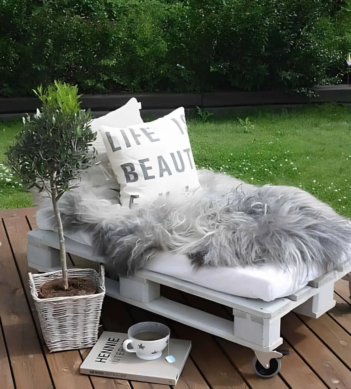 带有蓬松灰色毯子和图案靠垫的白色轮式午睡床