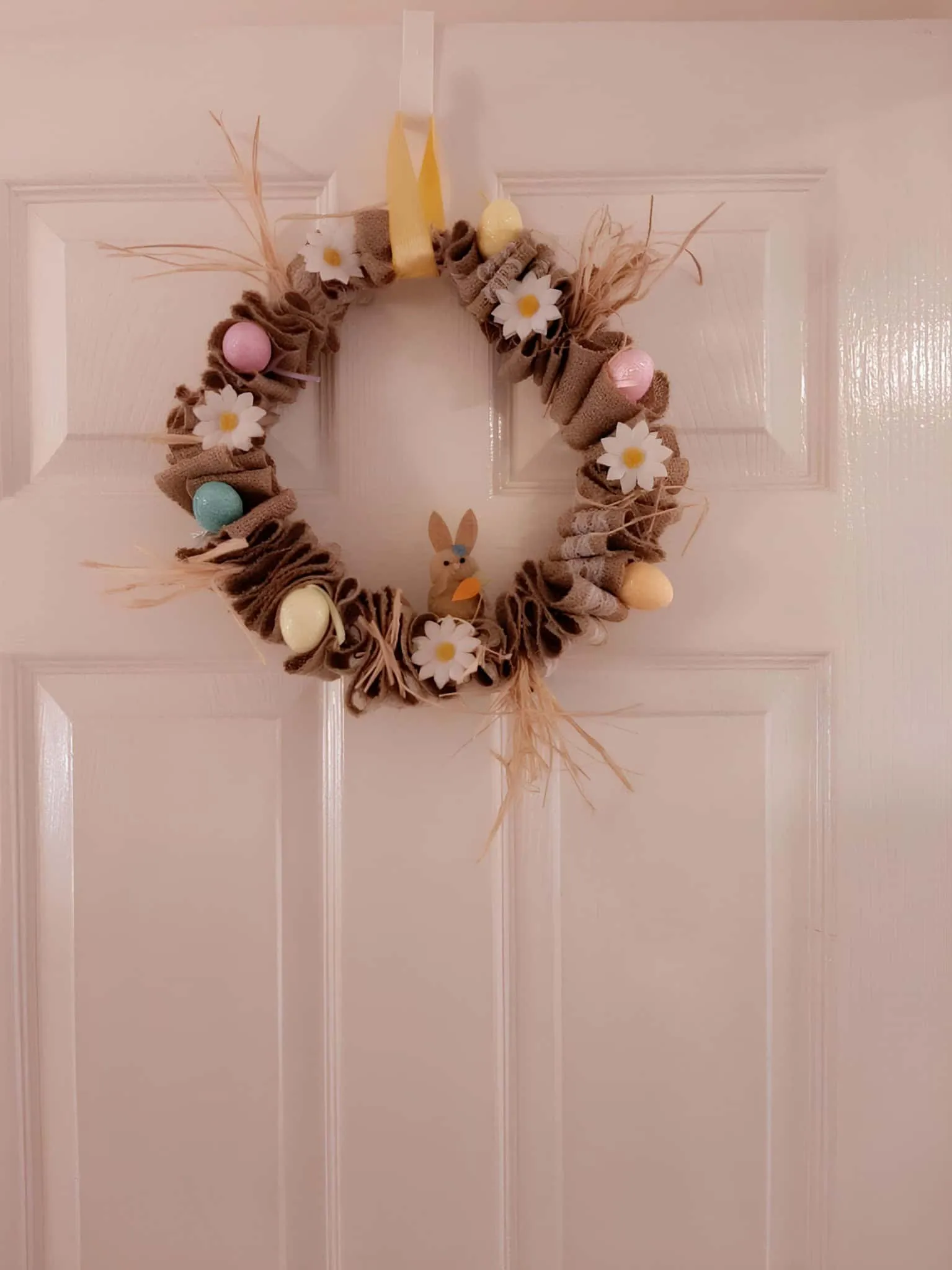 粗麻布门饰，配有胡萝卜、粉彩鸡蛋和鲜艳的黄色丝带用于悬挂