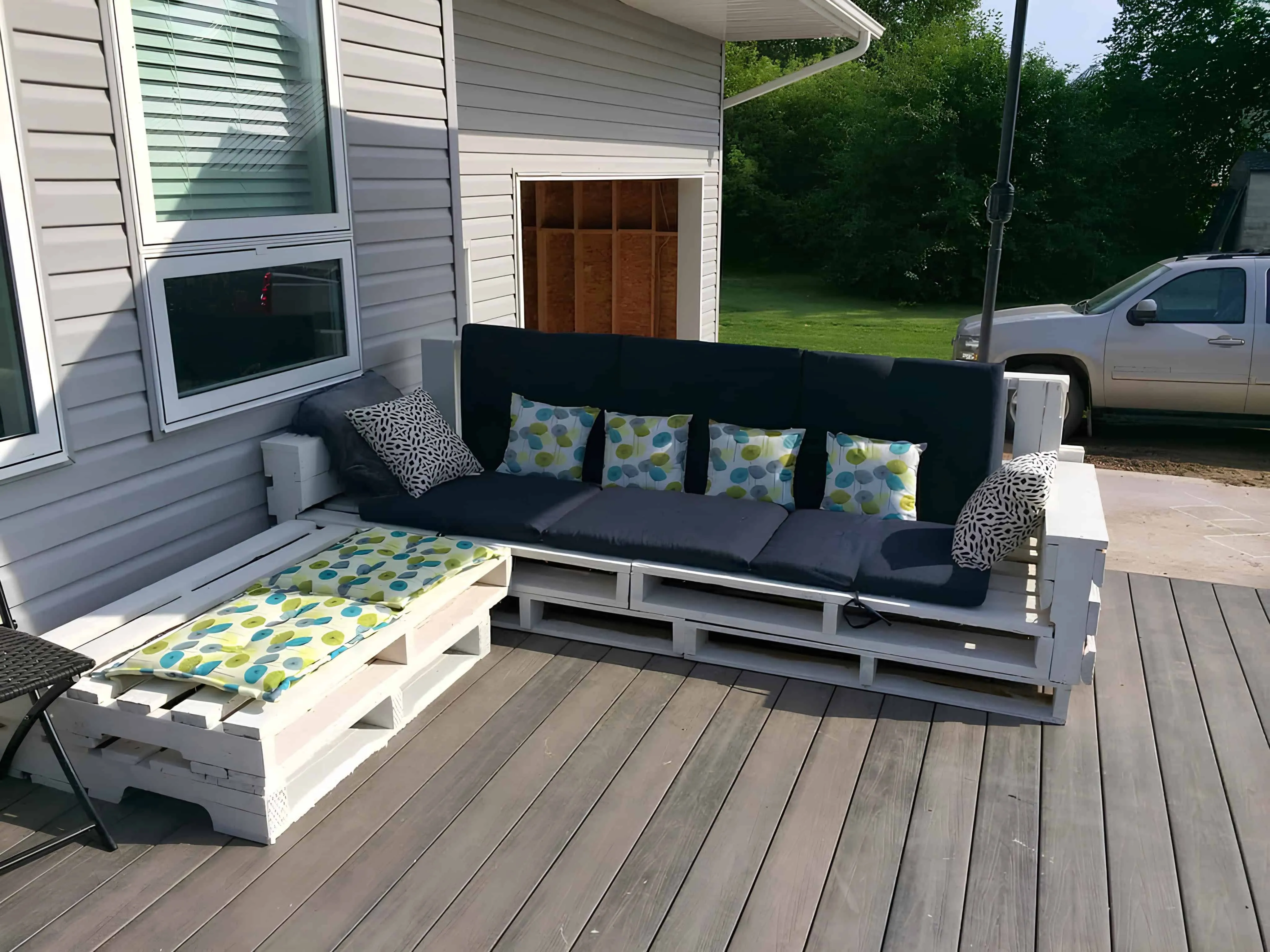 在露台上，大型L形白色托盘沙发，配有图案靠垫