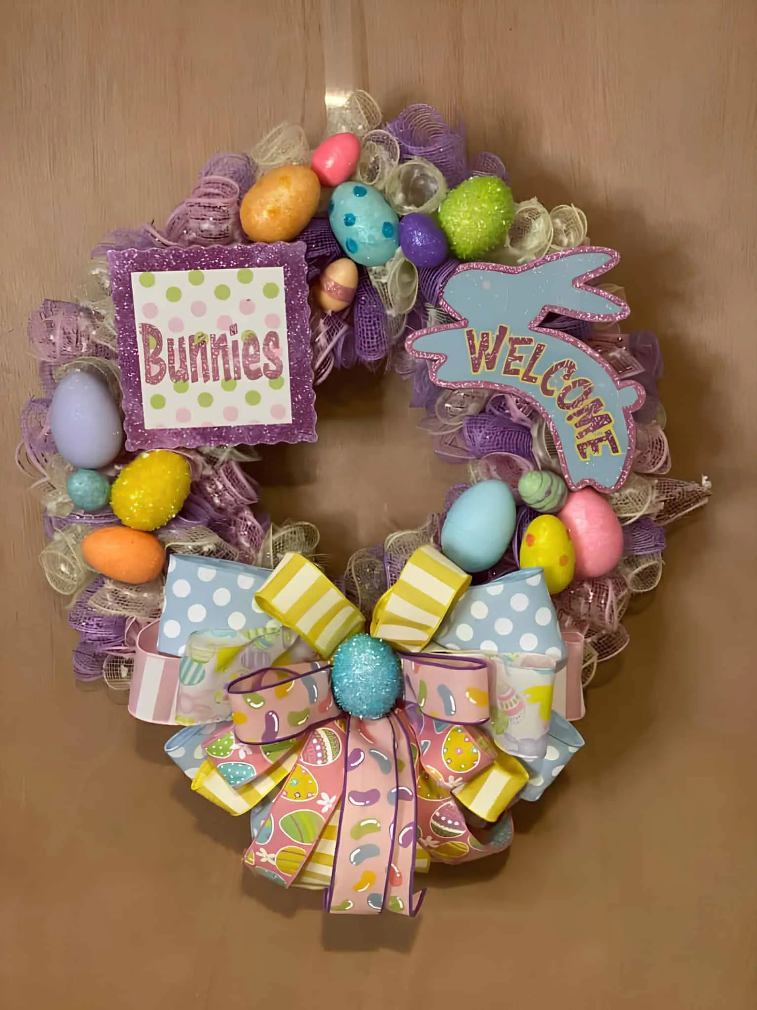 鲜艳的复活节门饰，配有彩色网、兔子和欢迎标志