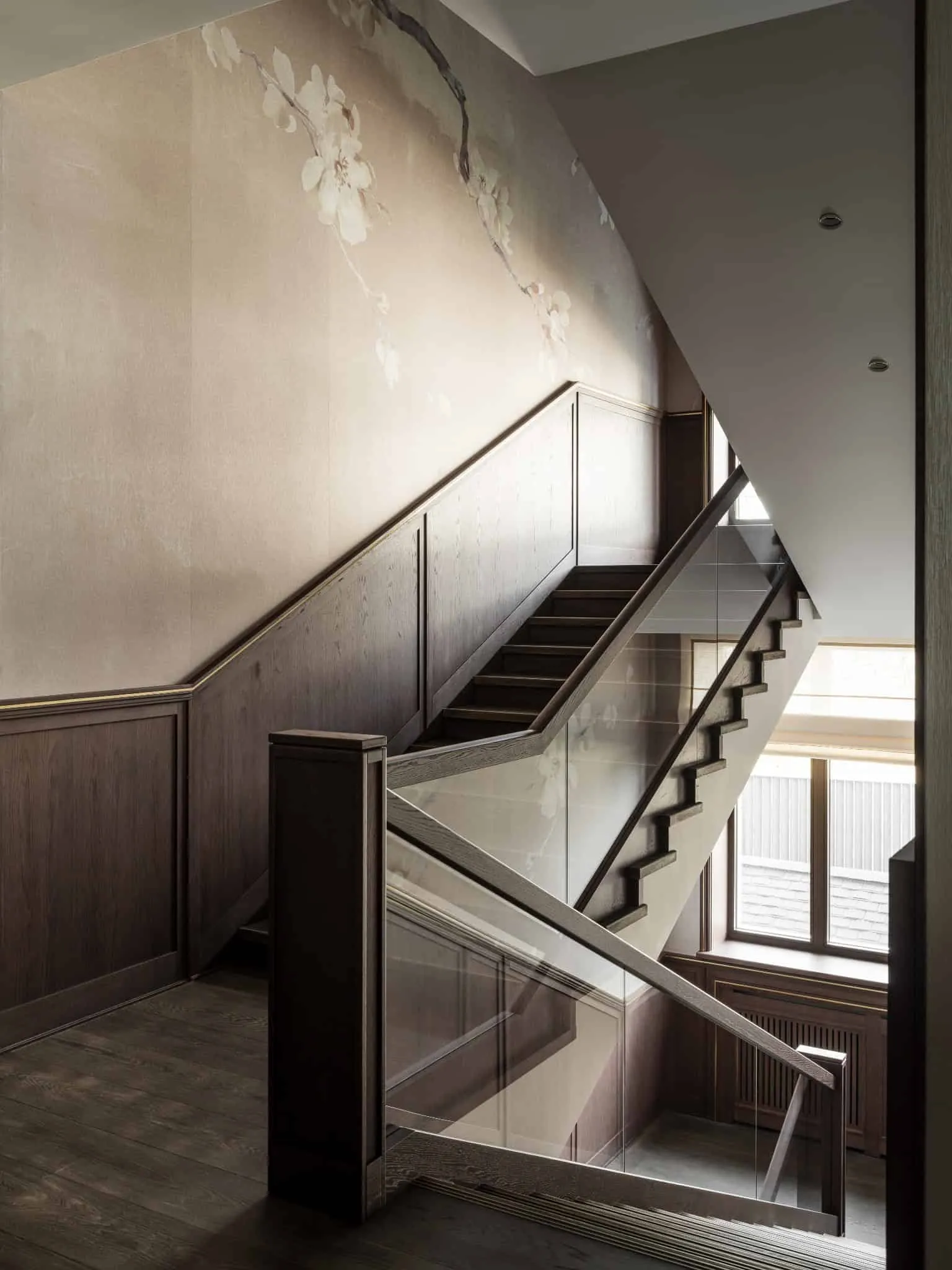 Елегантні сходи з скляним огорожею і квітковим оформленням стін.