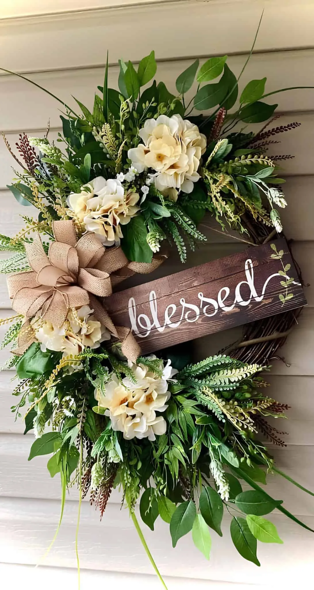 配有奶油杜鹃花、丰富绿叶、粗麻丝带和欢迎标志的春季门饰