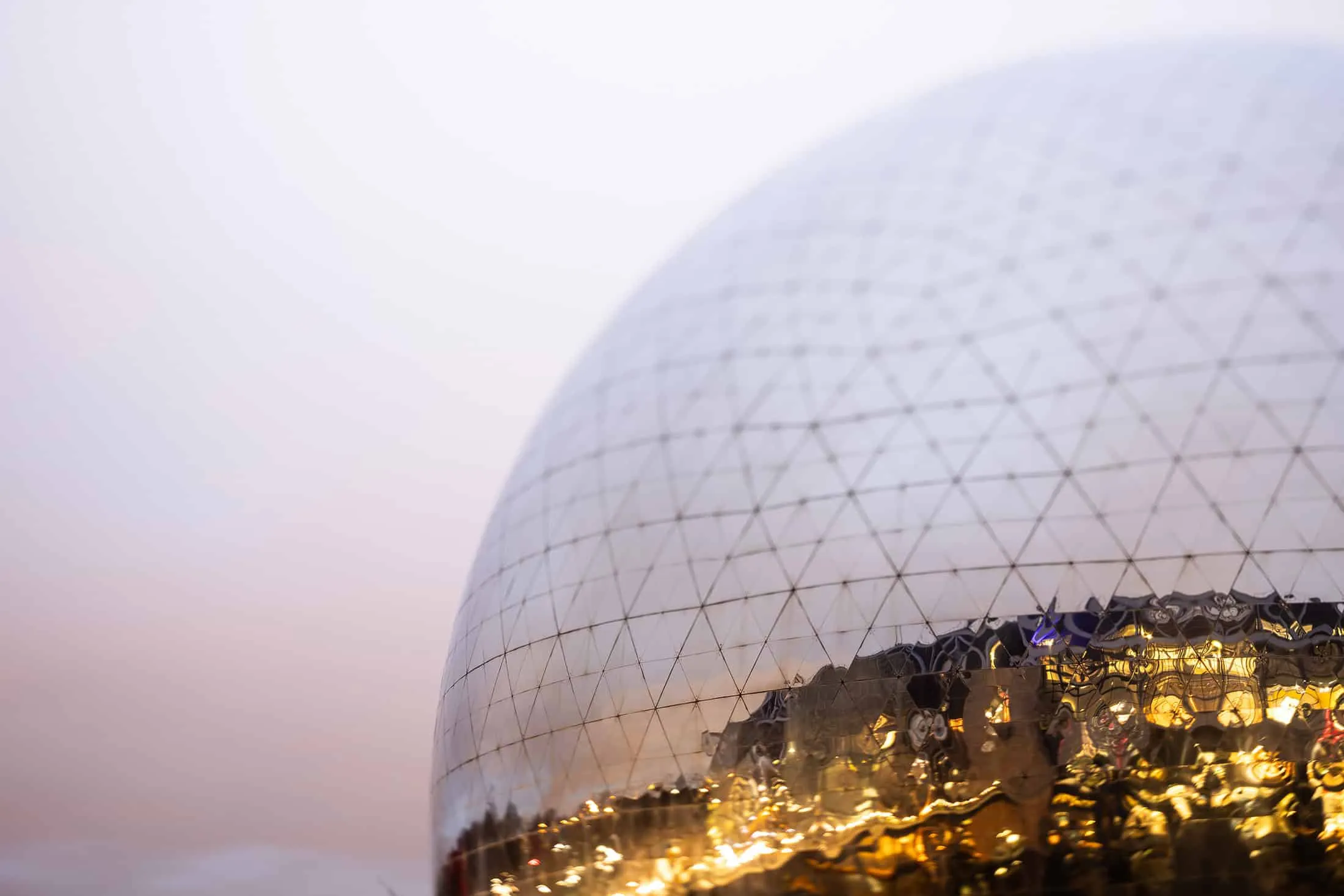 Close-up of the reflective mirror dome La Géode with geometric patterns.