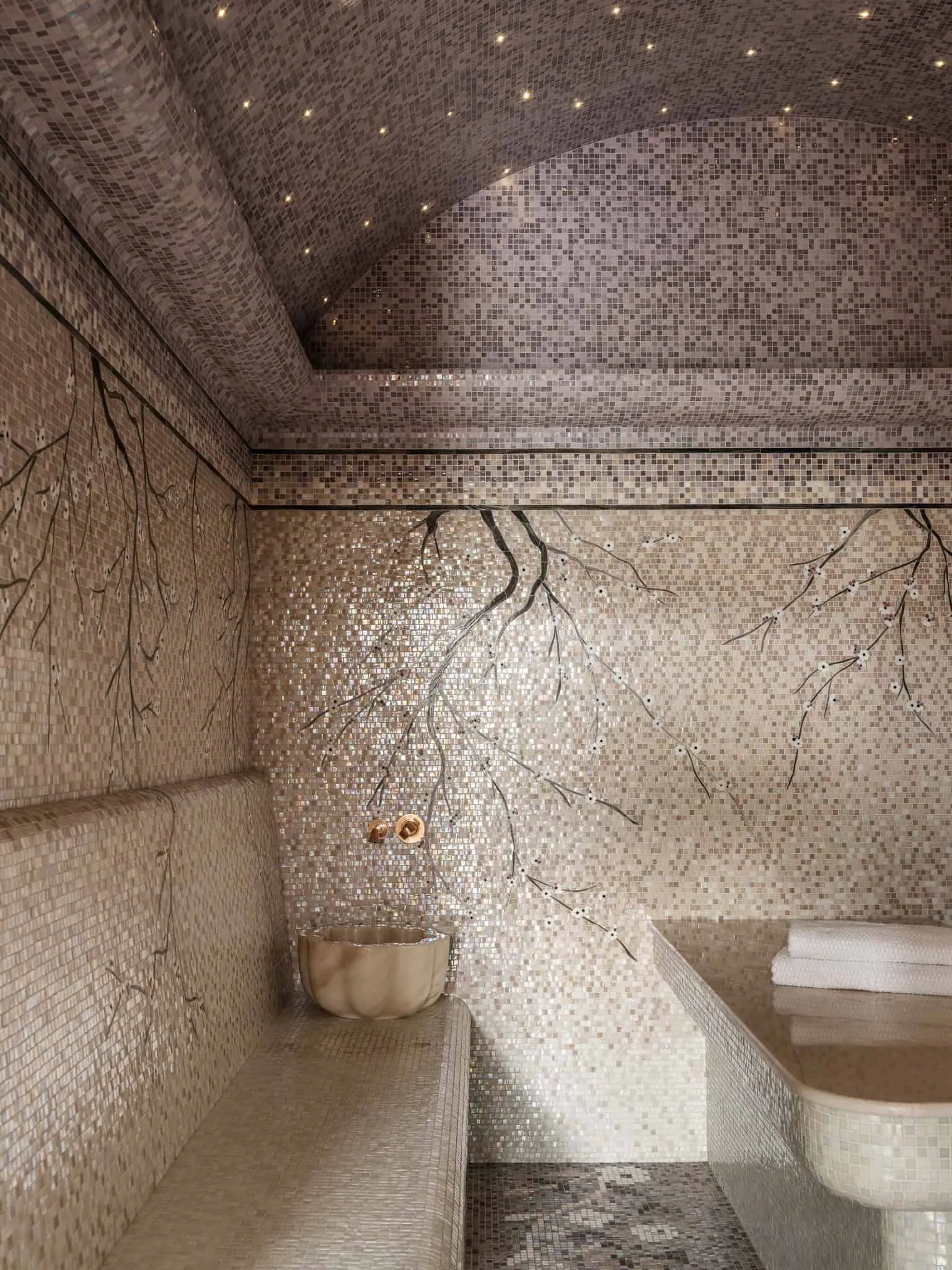 Спа-ванна кімната з золотими кранами, природними кам’яними мисками і світяться освітленням.