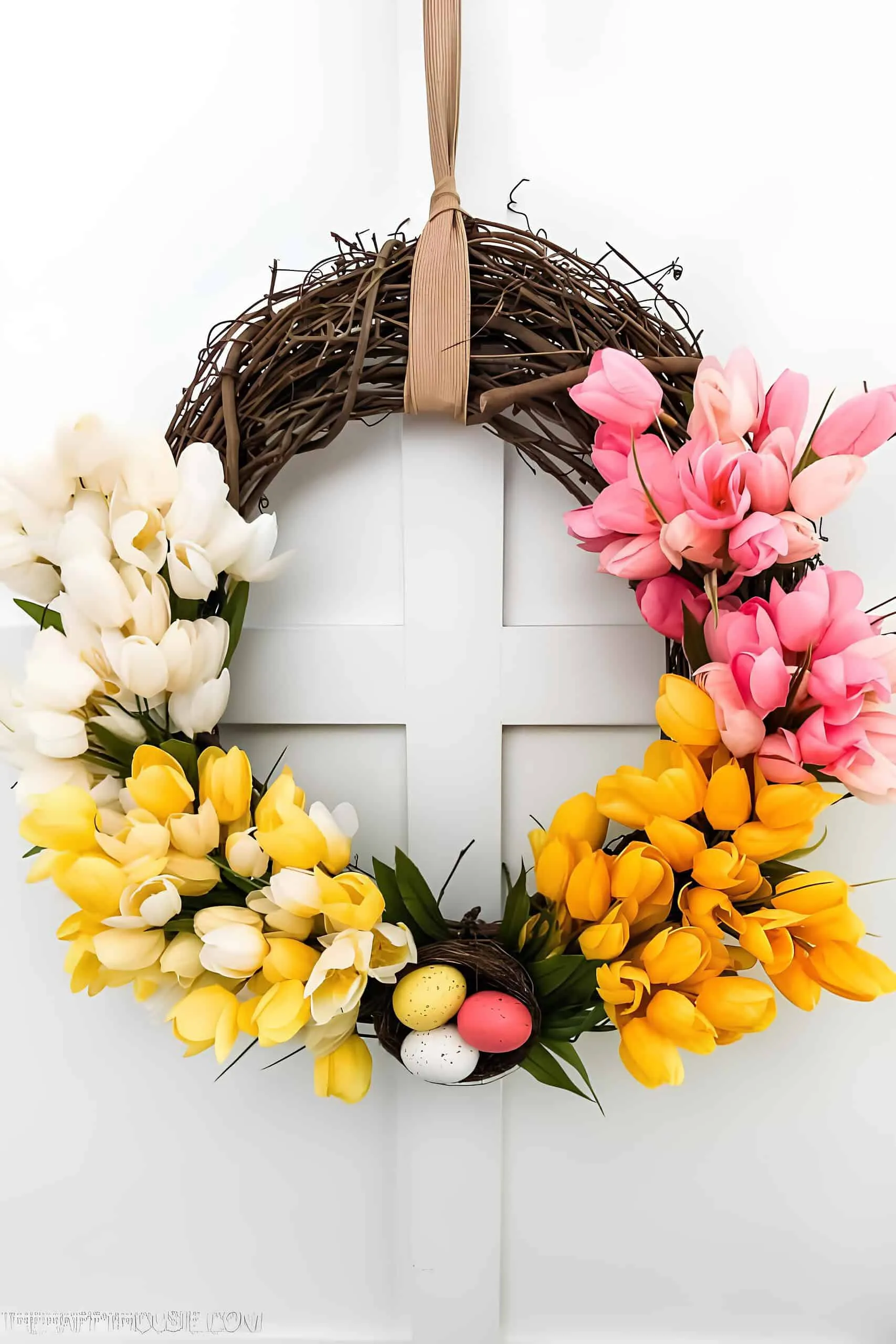 鸡蛋门饰，配有藤蔓底座并装饰有粉色、白色和黄色郁金香以及底部的鸟巢鸡蛋。