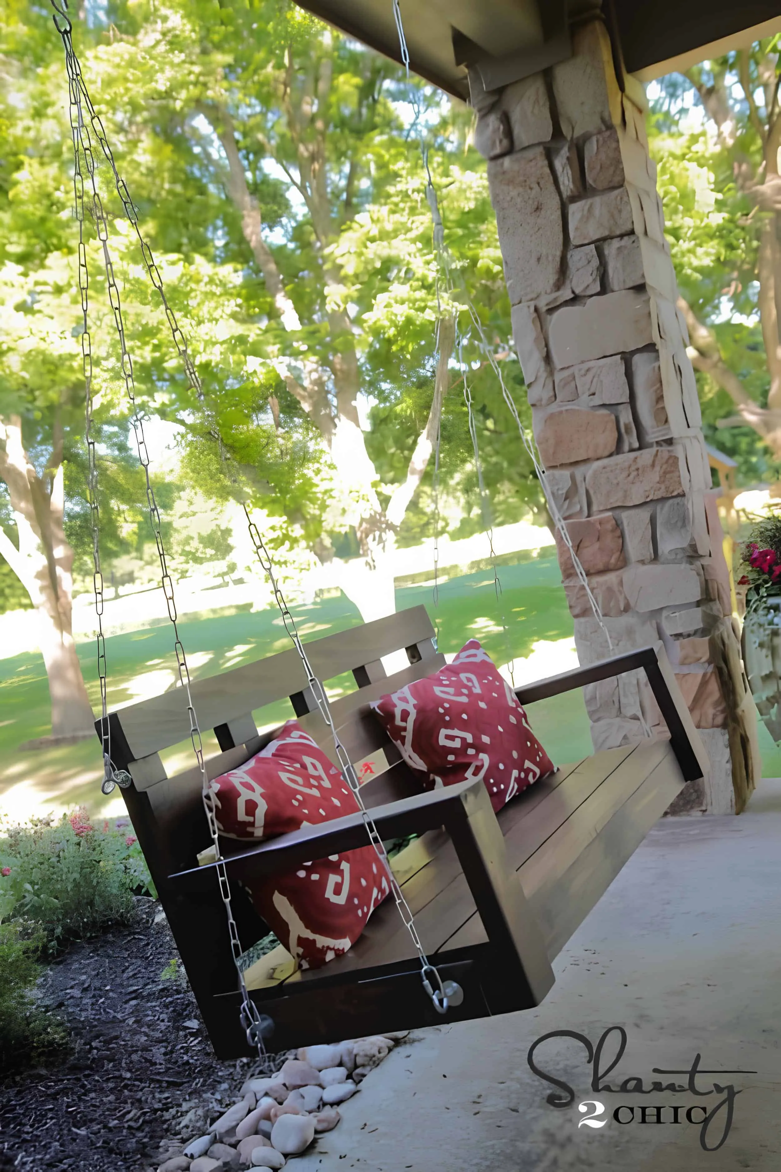 在露台上悬挂的深色木制长椅，配有红色图案靠垫