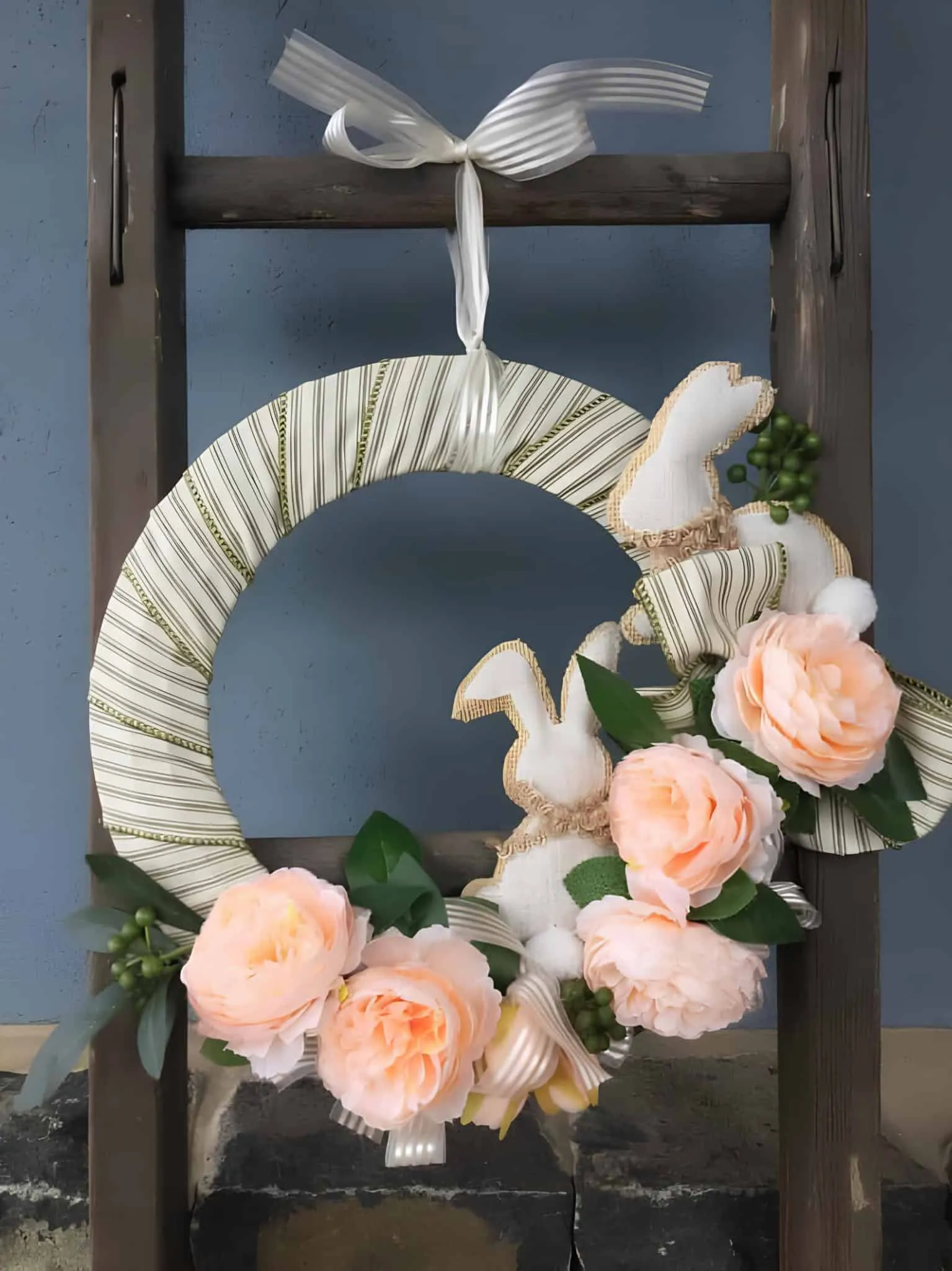 复活节门饰，配有条纹兔子和桃色花朵装饰