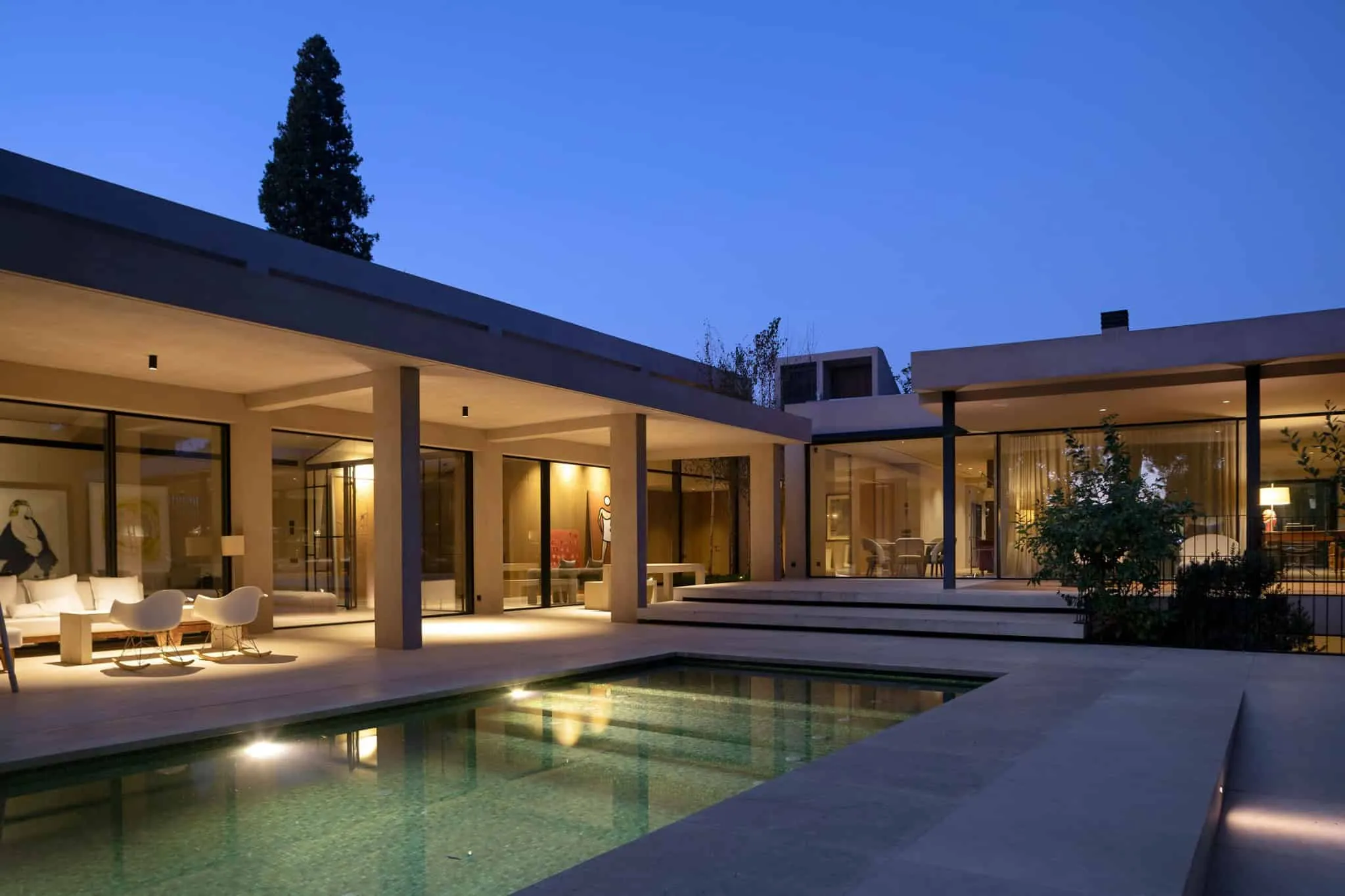 带照明内饰和泳池的现代住宅，反射温暖光线。