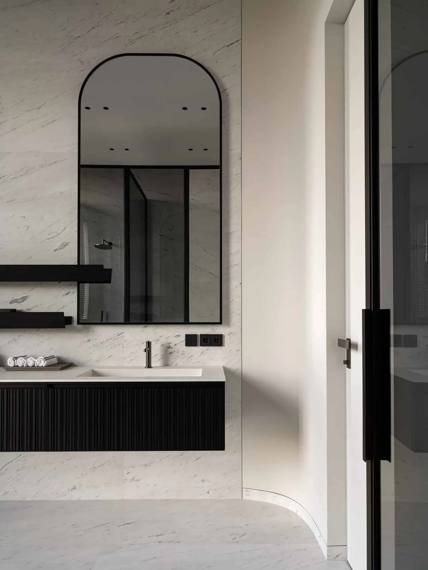 拱形镜子与浮动洗手台的现代浴室。