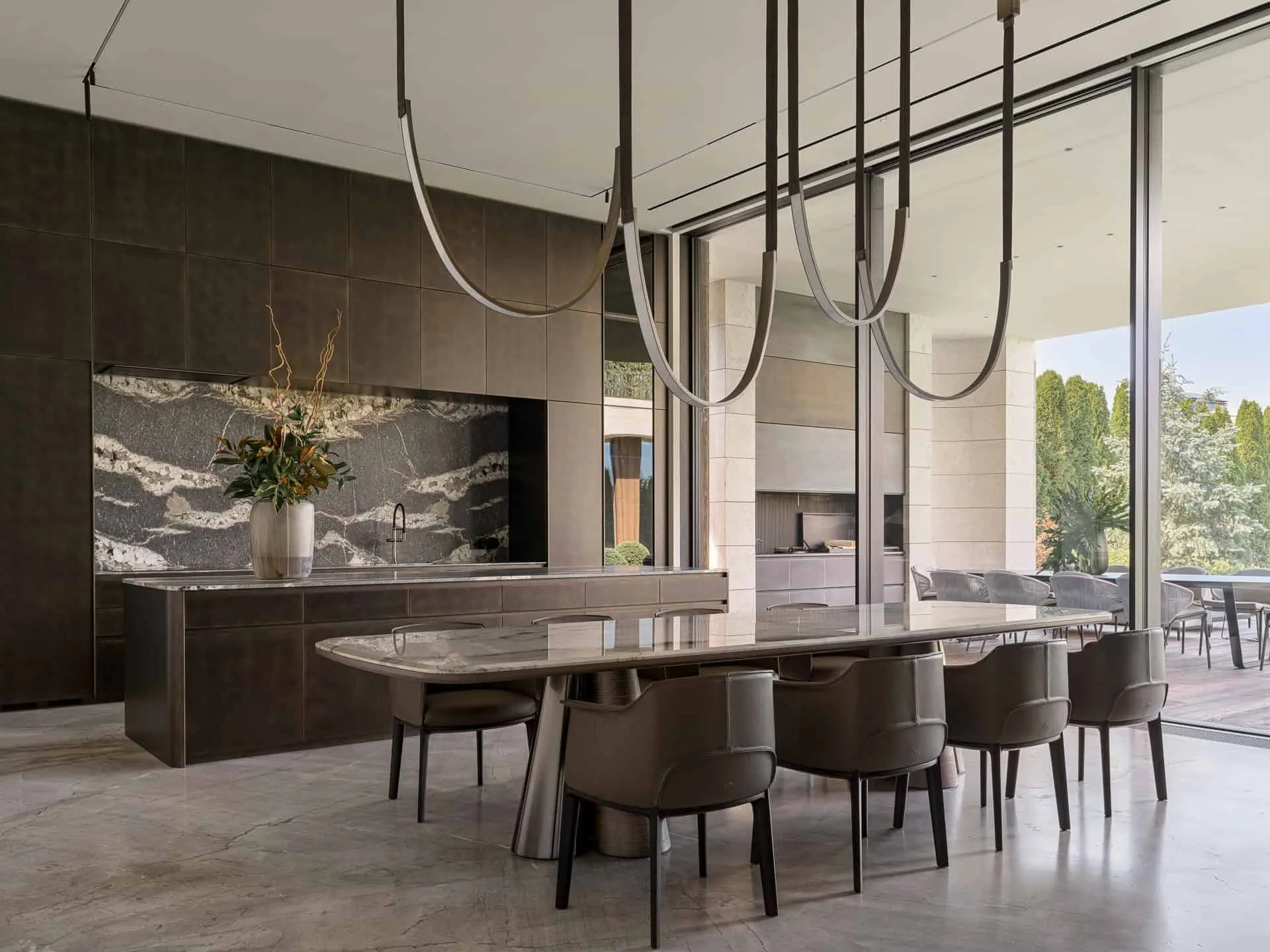大型大理石厨房岛与时尚餐桌，配有悬挂式灯具。