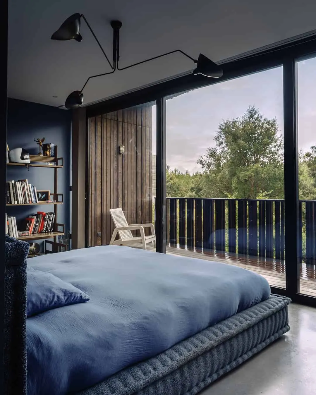 温馨的蓝色墙壁卧室，直接通往面向森林的阳台。