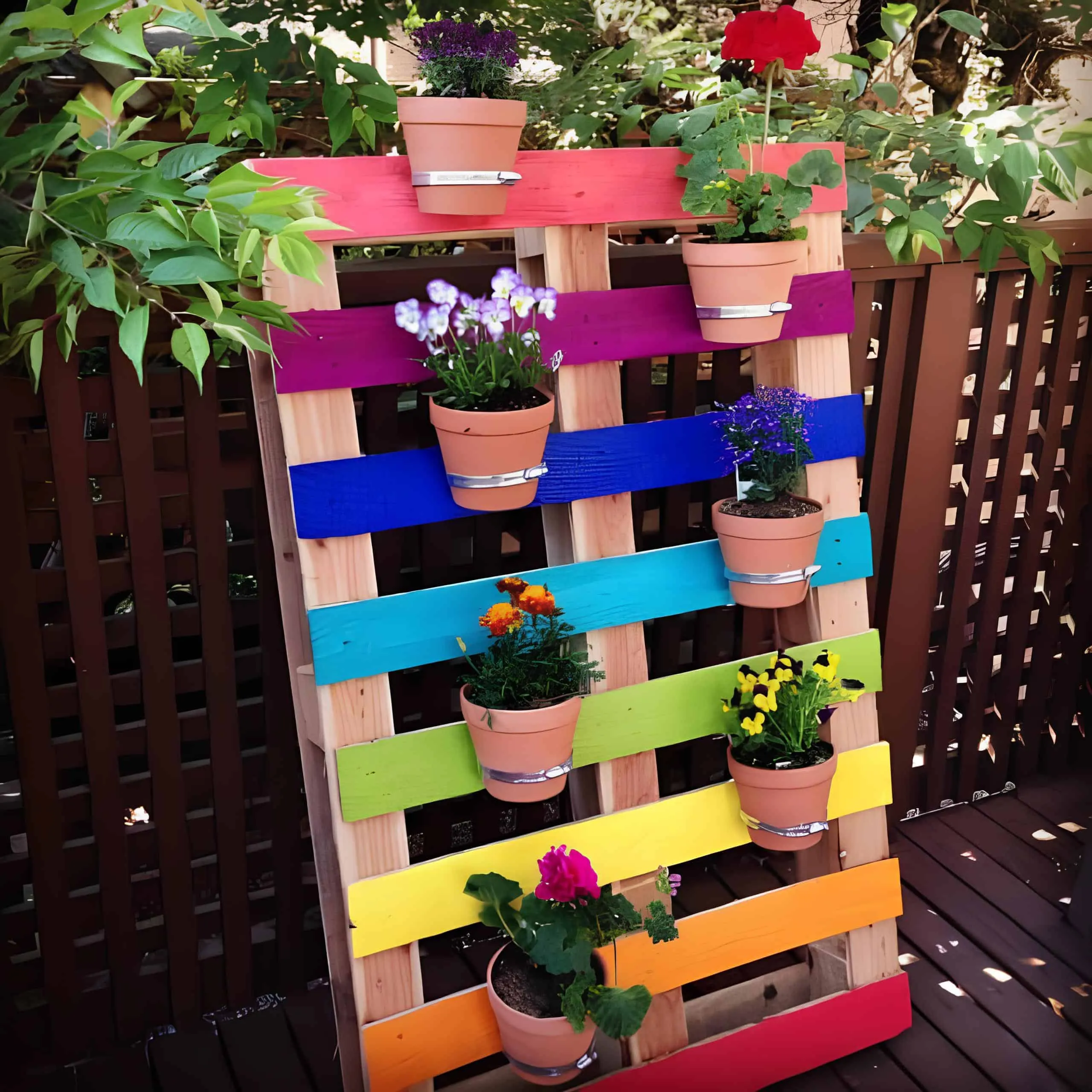 涂成彩虹色的托盘垂直花园，配有花卉花盆