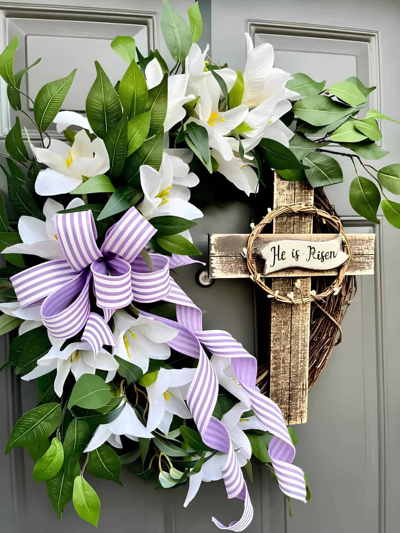 配有木制十字架、百合花、绿叶和紫色条纹丝带的门饰