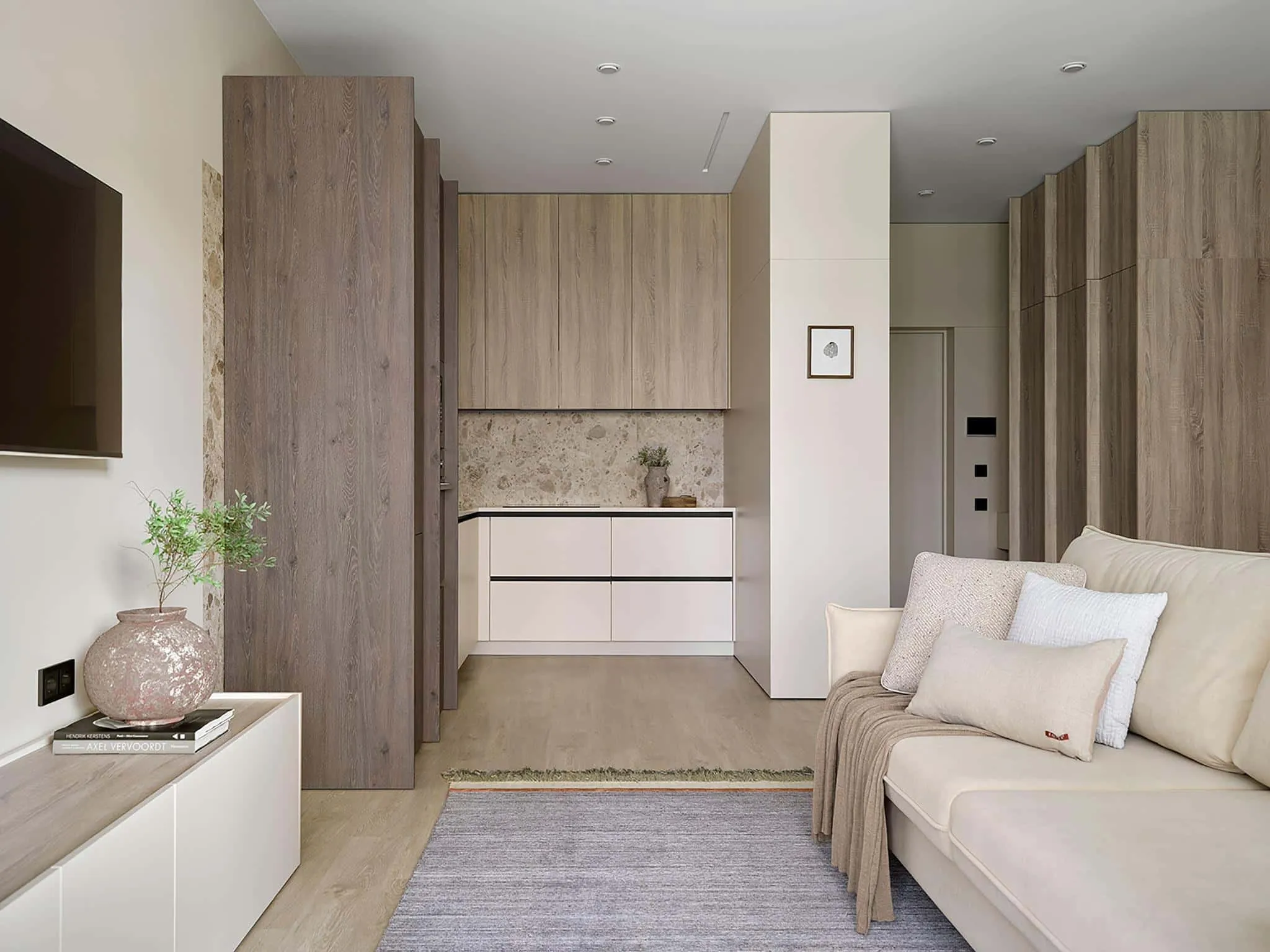 带有米色沙发、内置衣柜和中性厨房装修的开放式客厅。