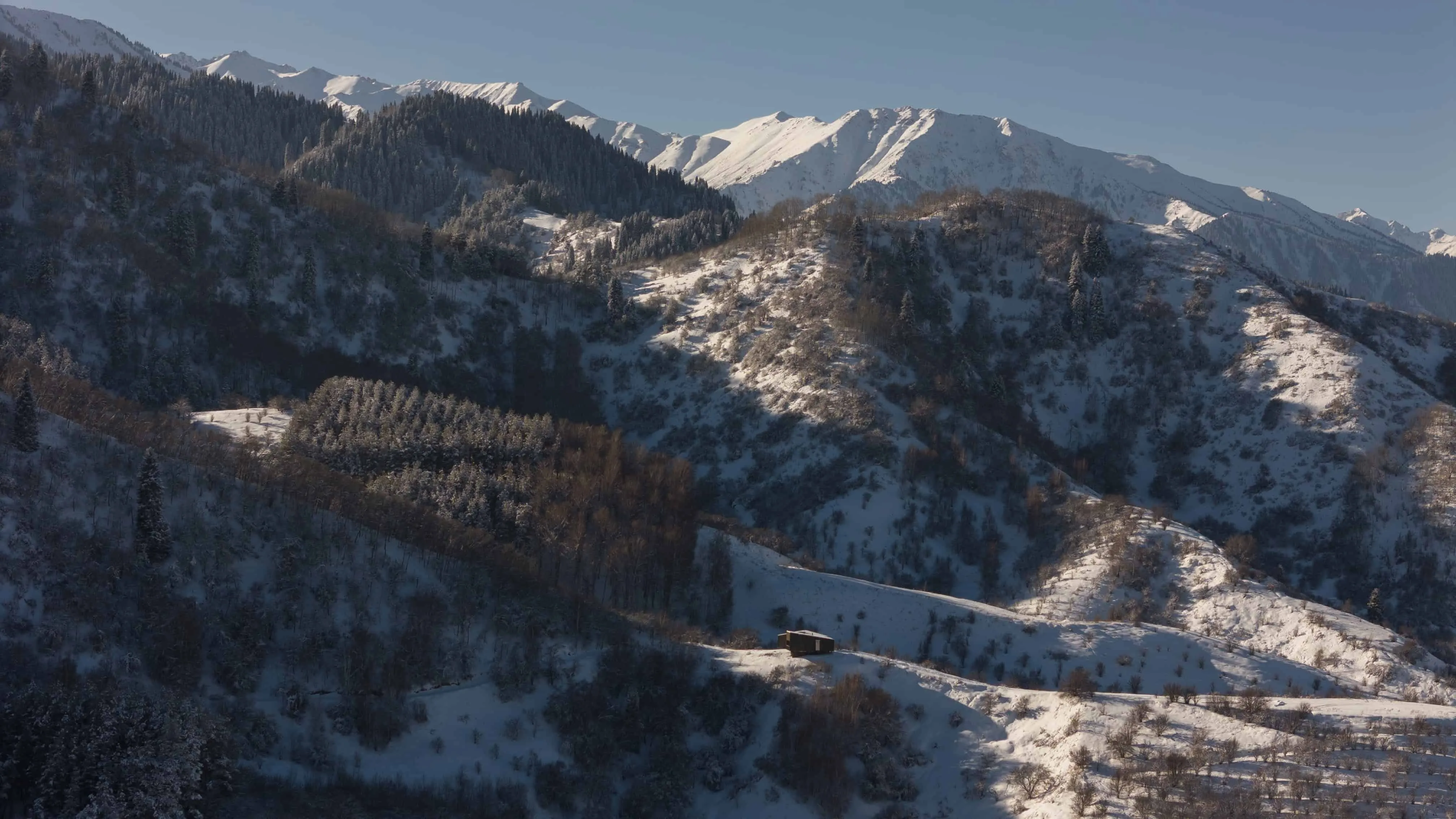 远距离空中视角，阿姆小屋坐落在哈萨克斯坦严峻雪峰中。