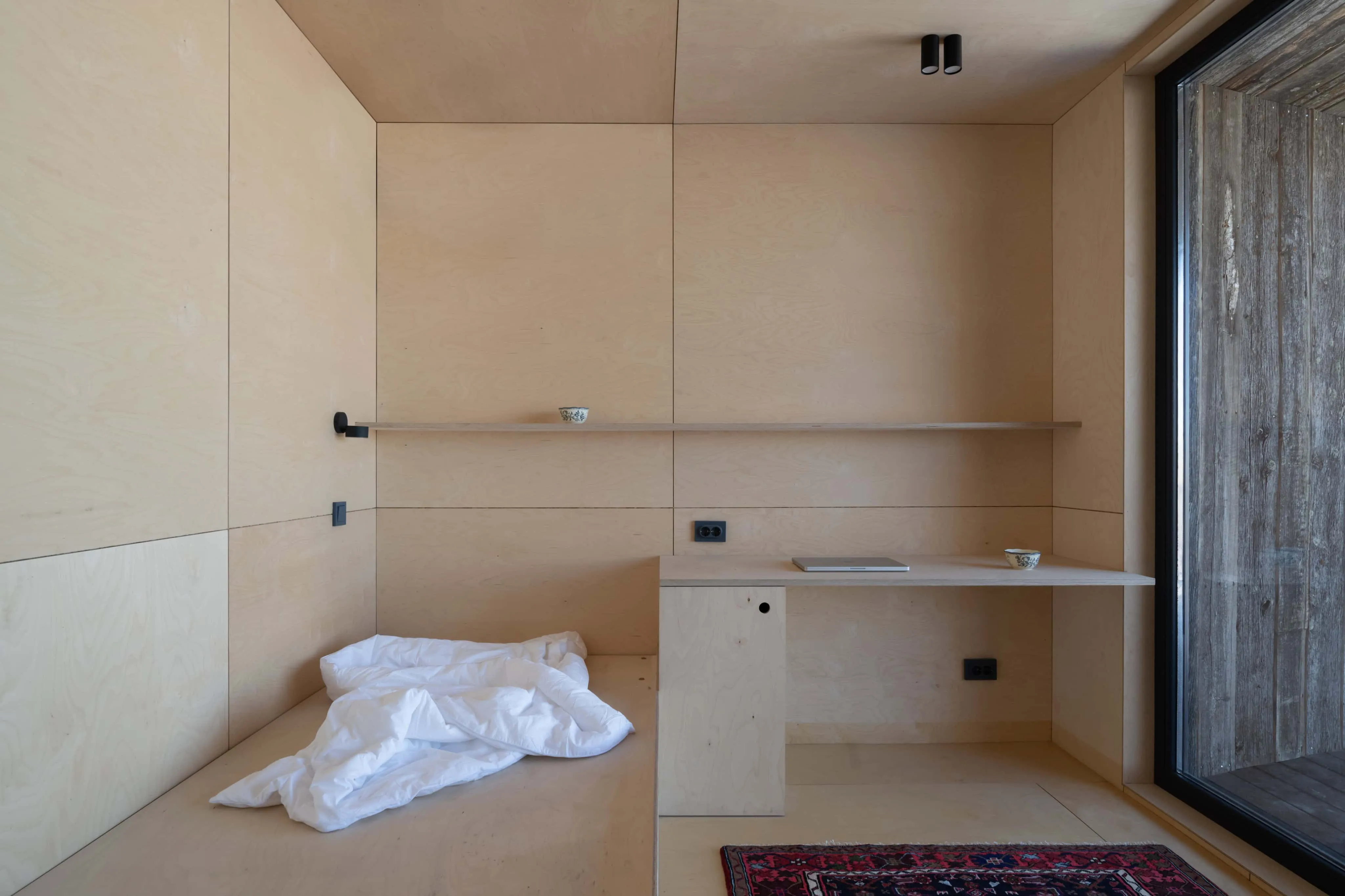 紧凑内饰，白桦木胶合板墙面、内置床和书桌。