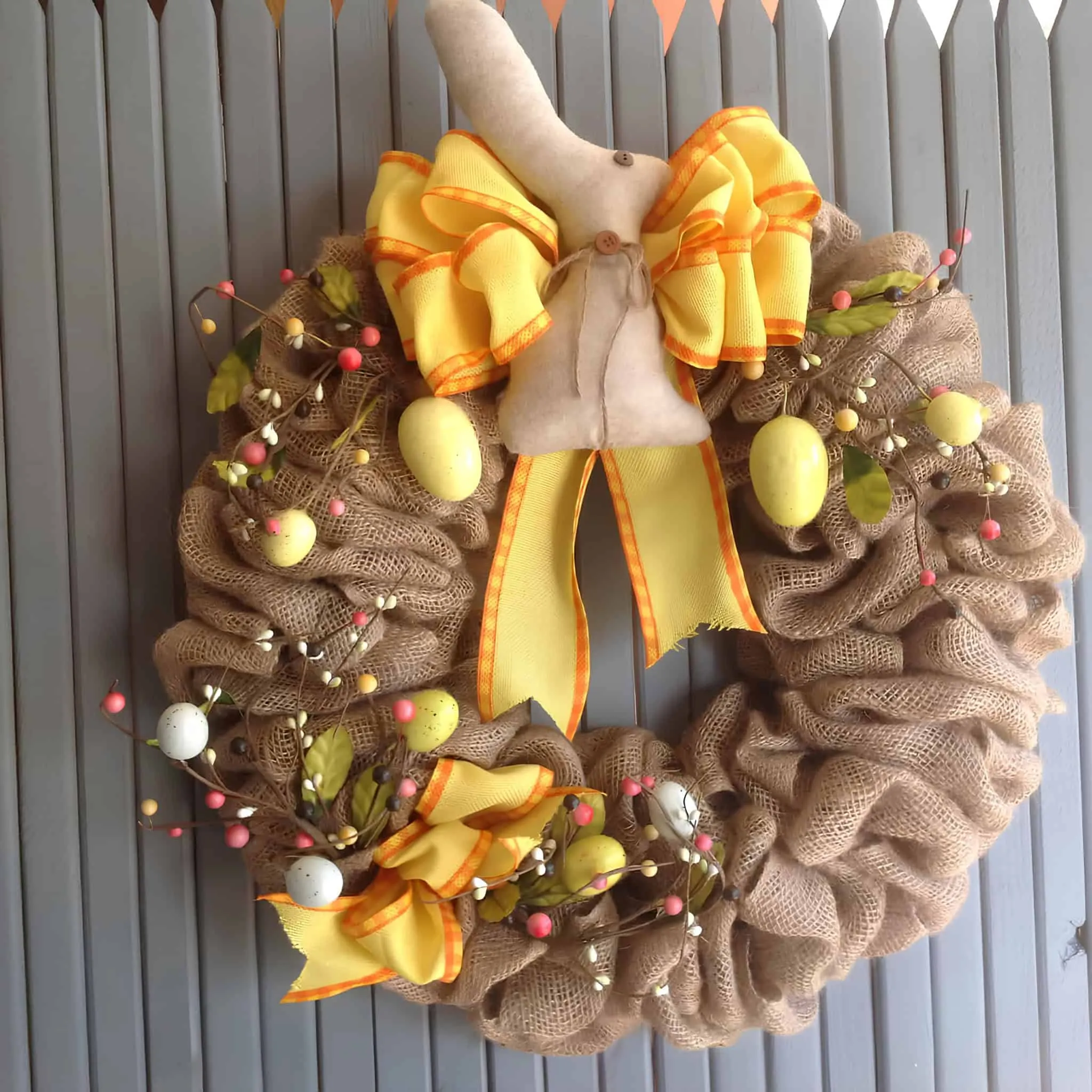手工复活节门饰，配有粗麻布、黄色丝带和装饰鸡蛋