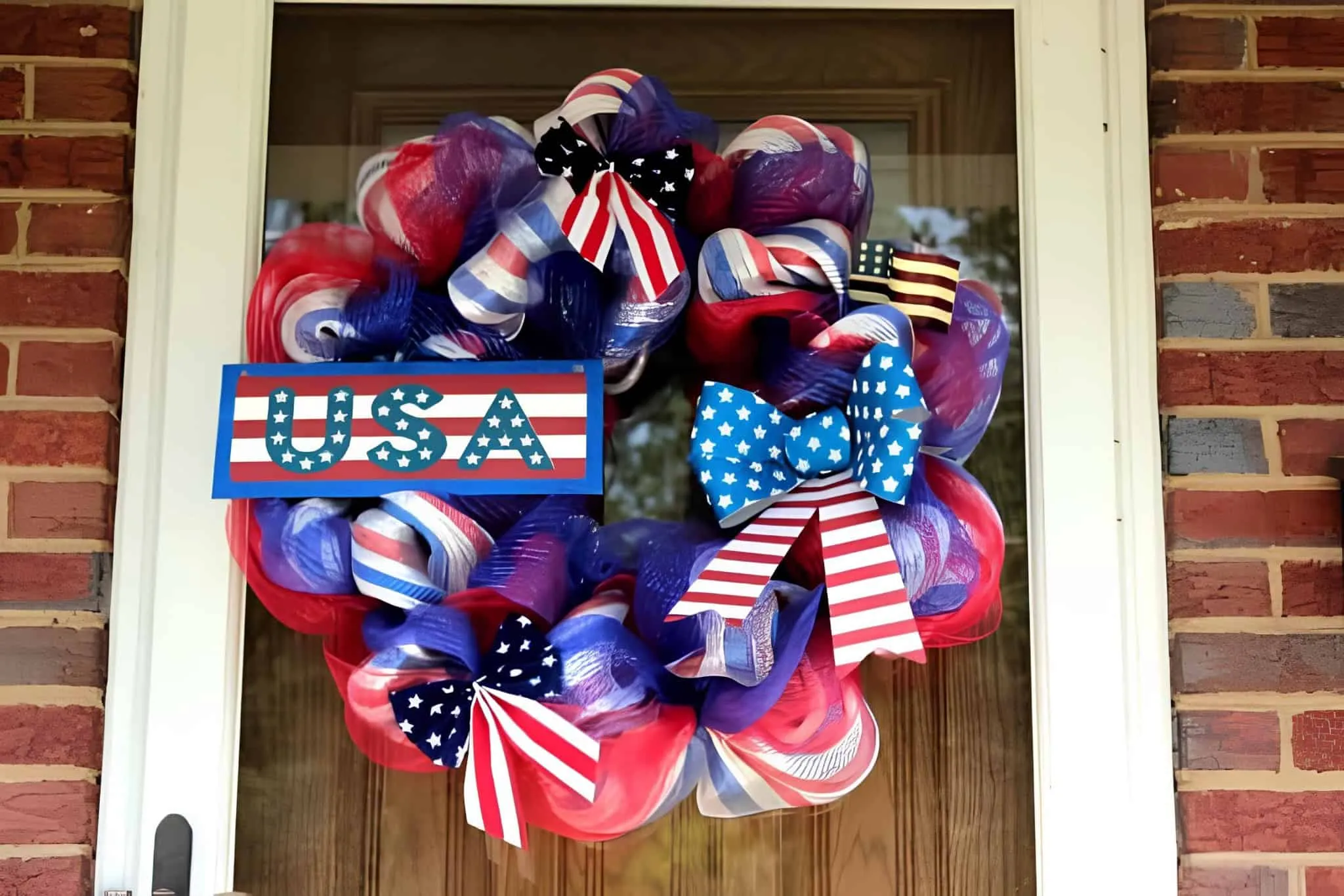 大胆的前门花环，由红、白、蓝装饰网格和条纹丝带制成