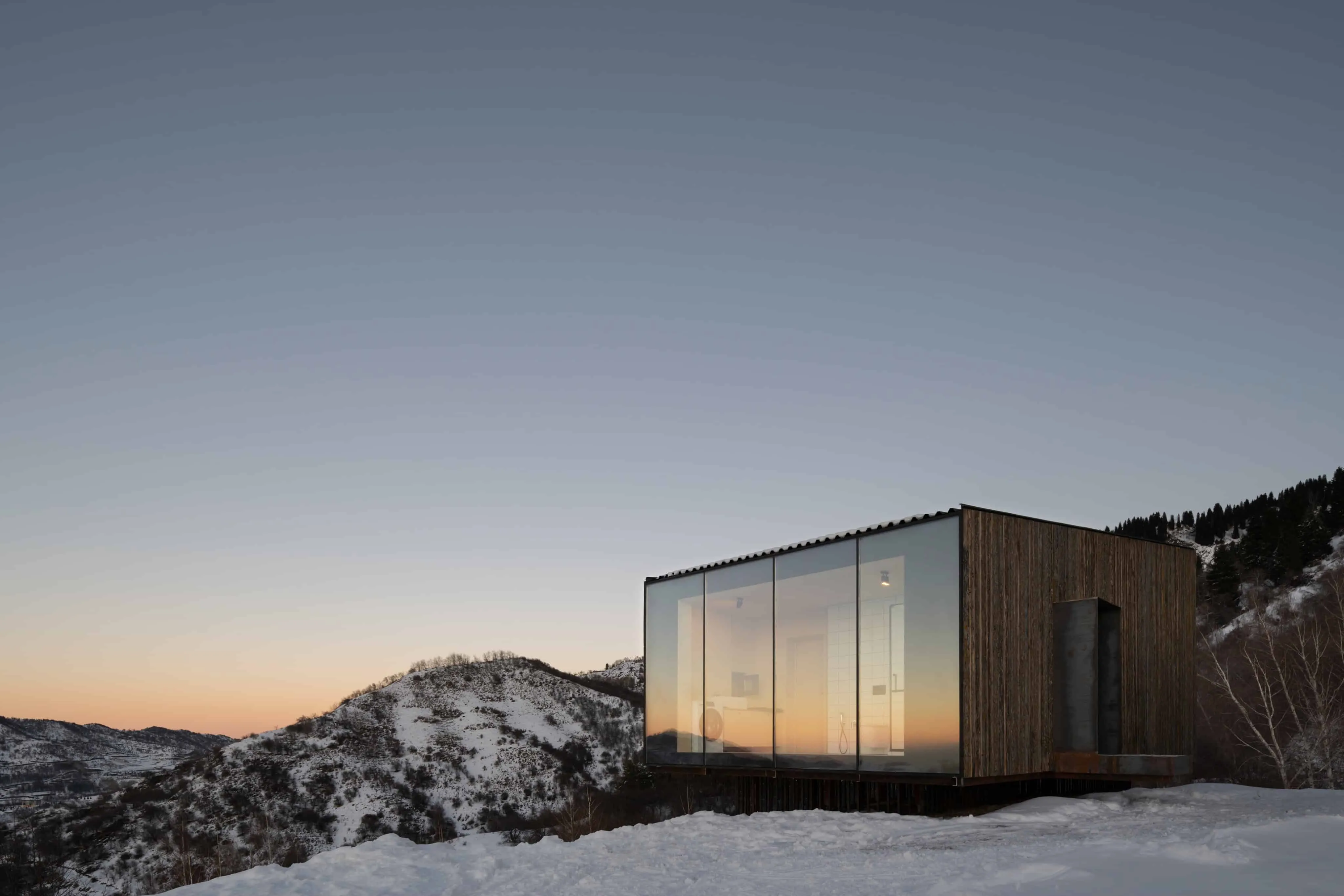 透明小屋在雪峰背景下散发温暖光芒。