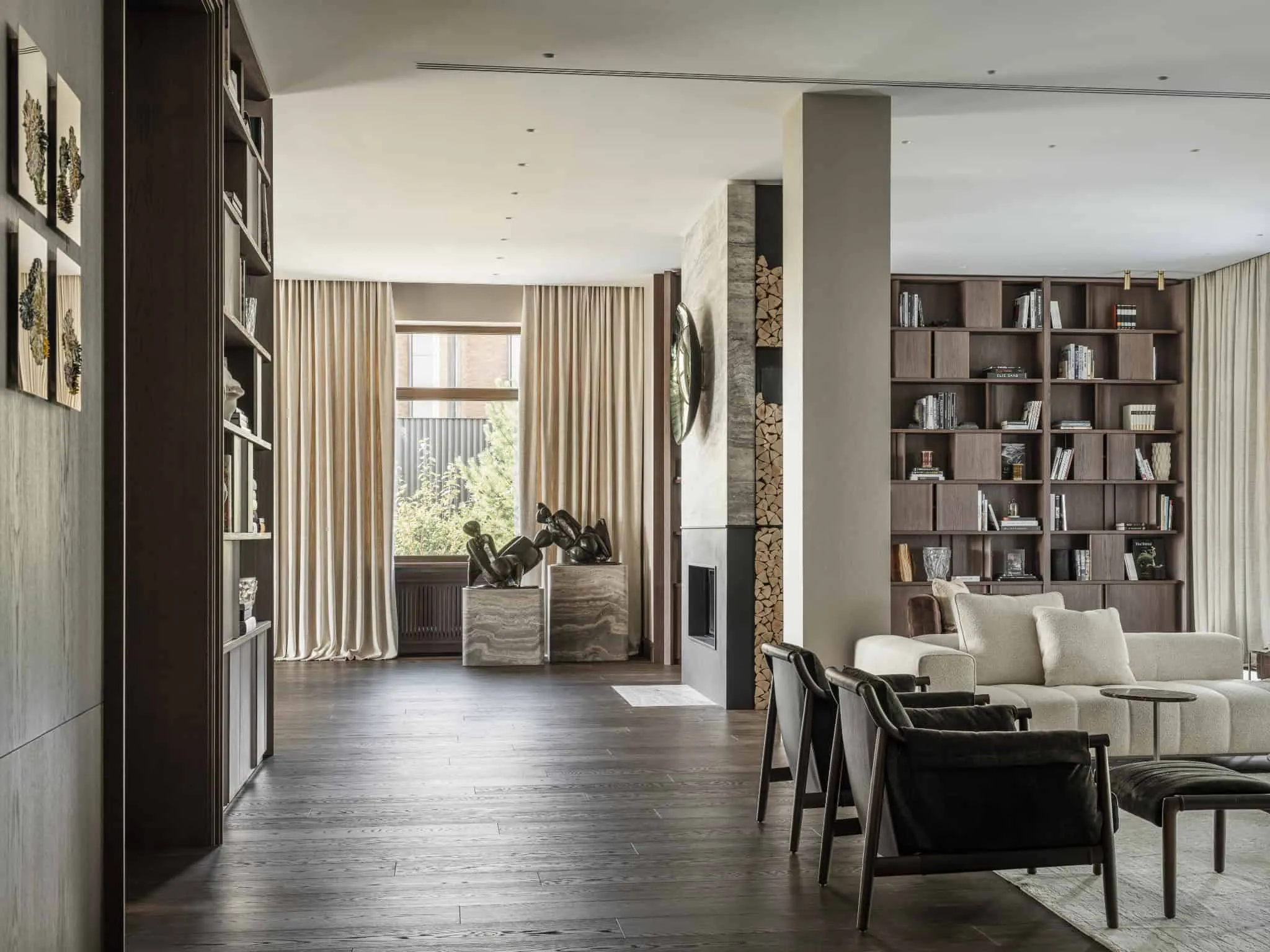 Розкішна гостиная з темним дерев'яною підлогою та природнім світлом від високих вікон.