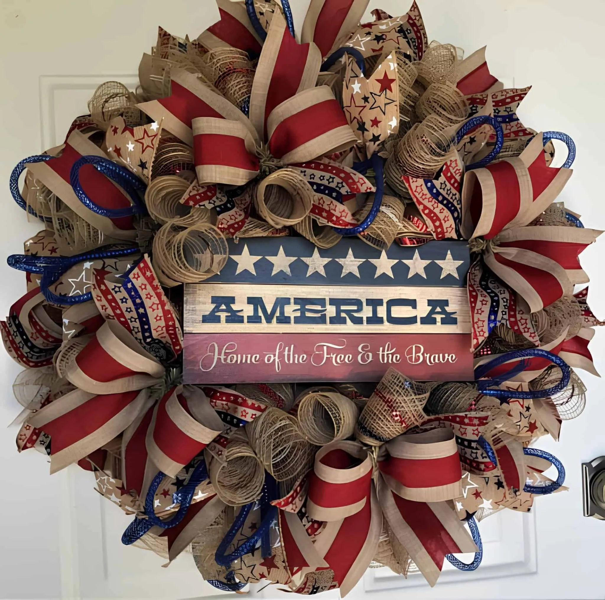 完整的爱国丝带花环，印有'自由和勇敢之屋'>完整的经典爱国色调花环，装饰着星星和条纹以及美国自豪的宣言。<h2>红门上的条纹花环</h2><img title=