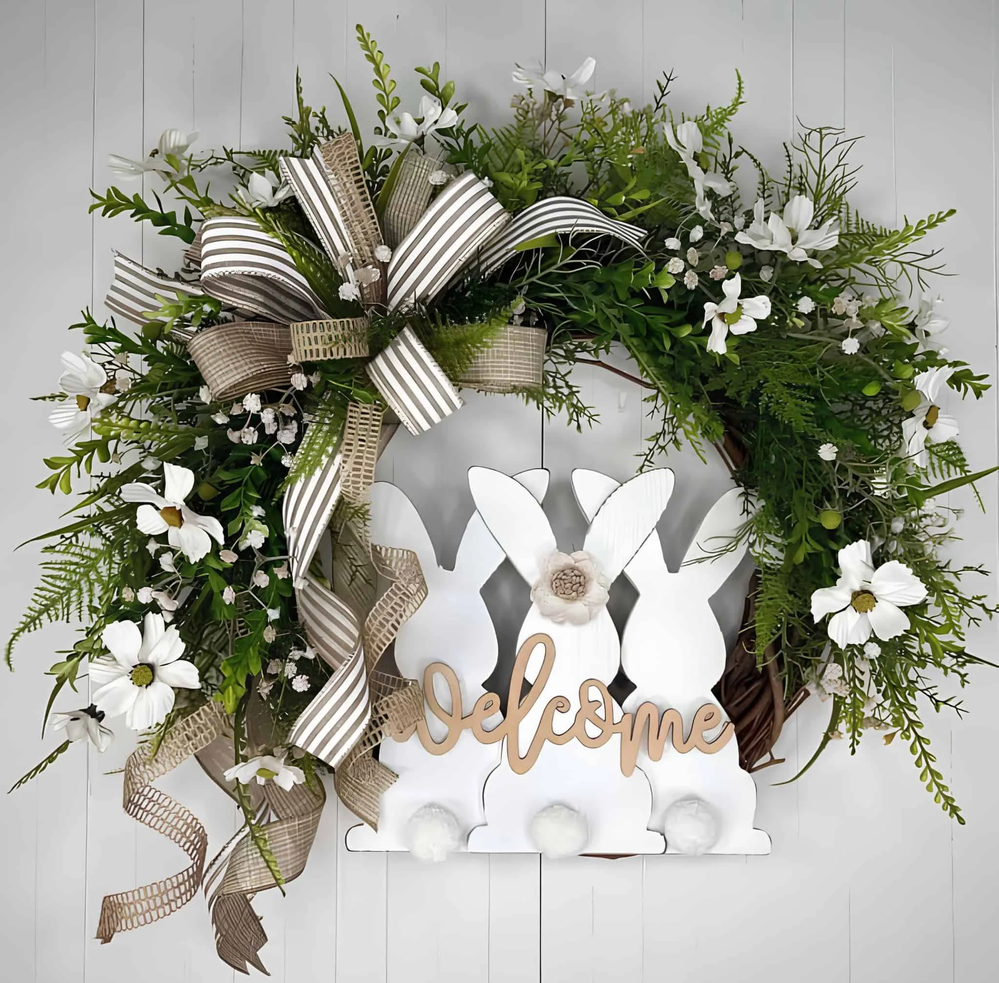 配有三个白色兔子轮廓、绿叶、白花和装饰条纹丝带的门饰