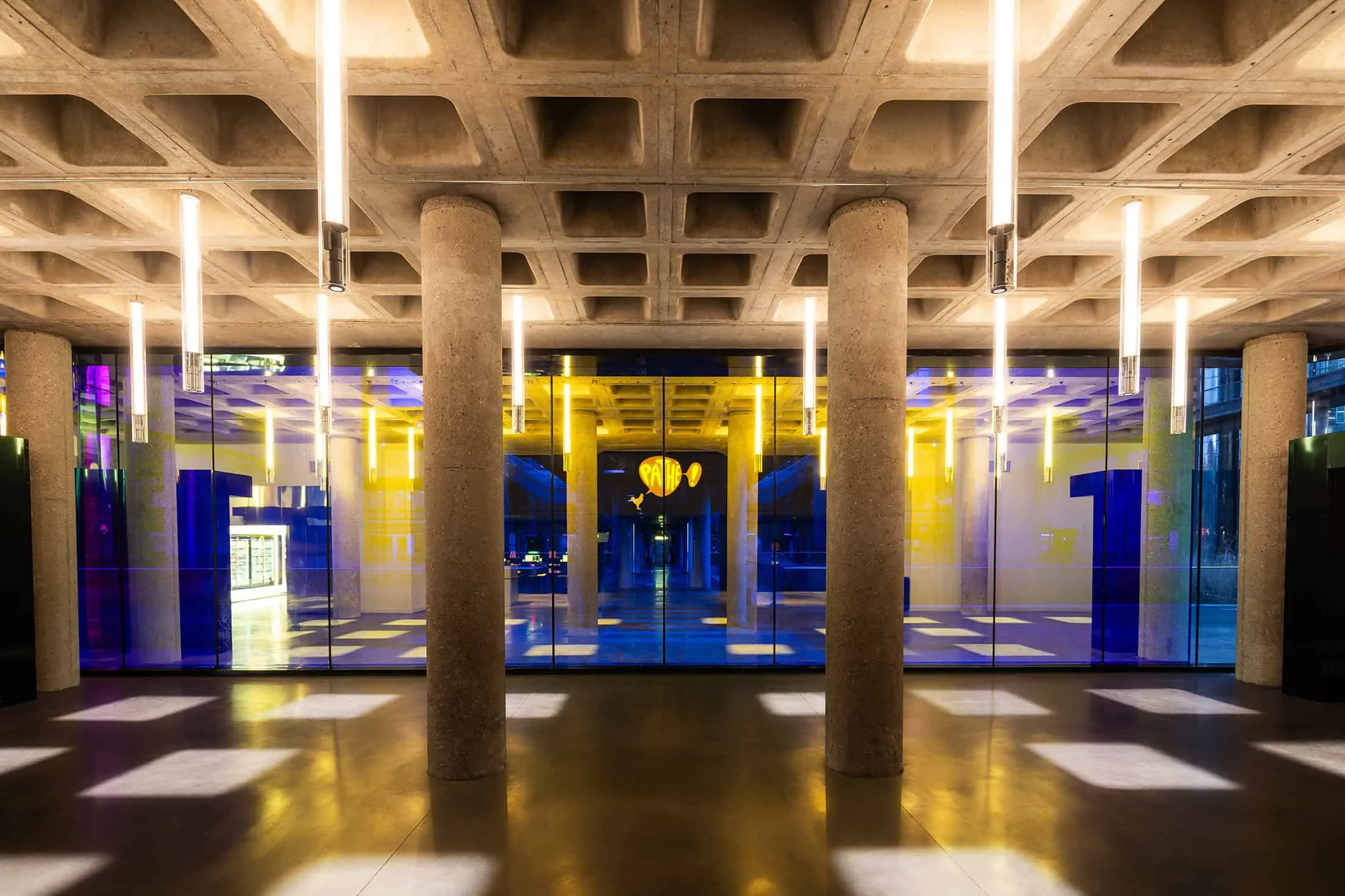 Lobby with concrete columns and colored glass panels in La Géode.