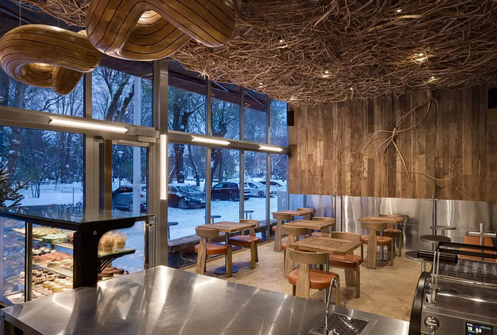 温暖晚间照明的温馨咖啡馆，配有树枝天花板和木质元素