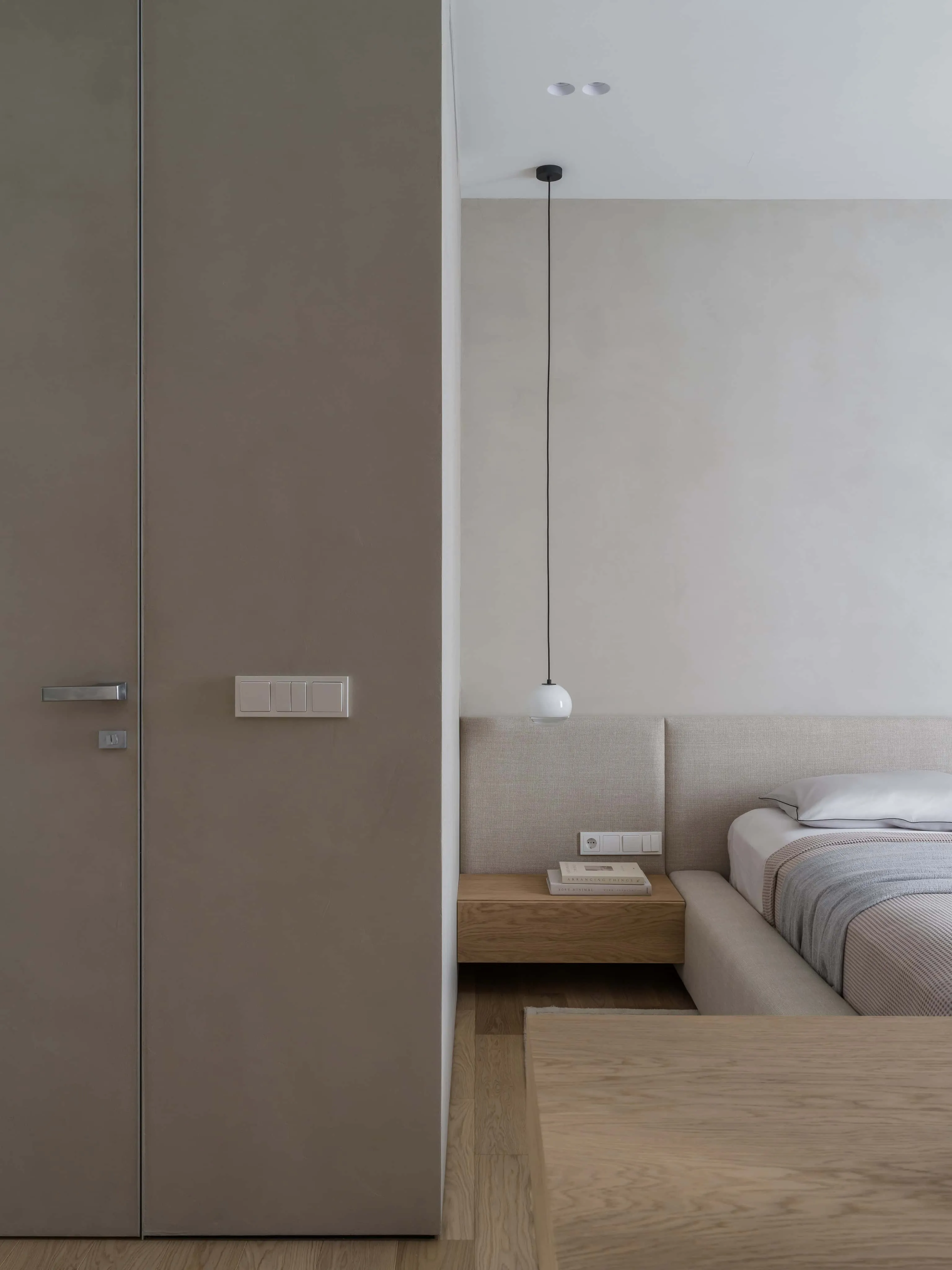 现代卧室，配有漂浮木质床头柜、吊灯及柔和中性窗帘。