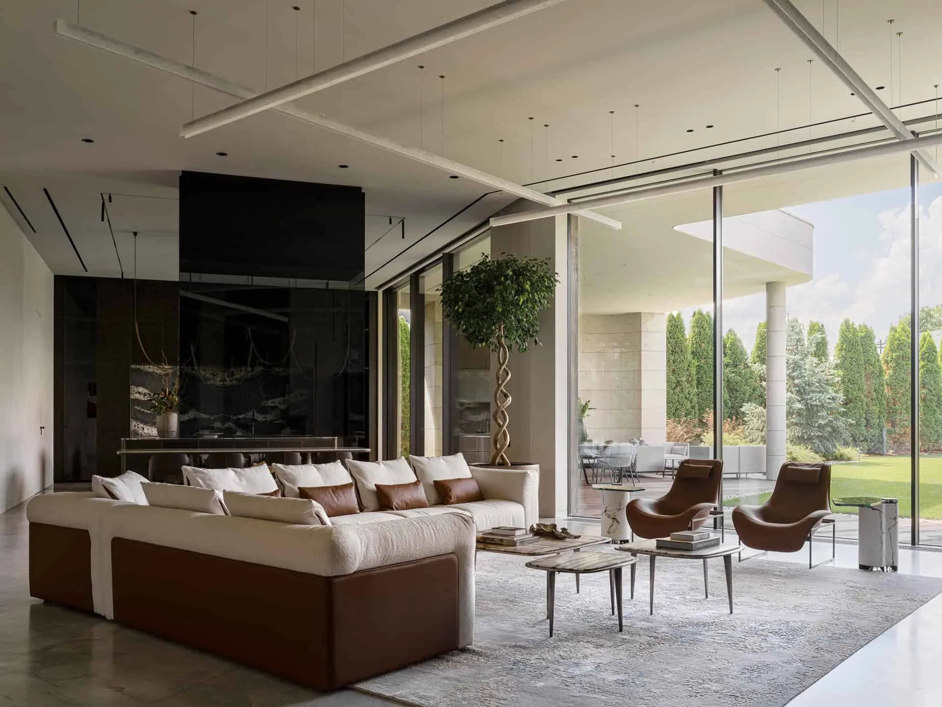 奢华客厅，配有柔软沙发和透过玻璃墙的开阔花园景色。