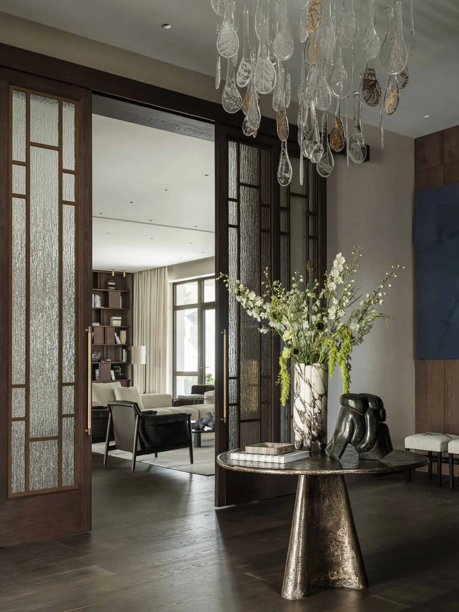 Крупний план мраморної вази з білими та зеленими квітами на бронзовому столі.