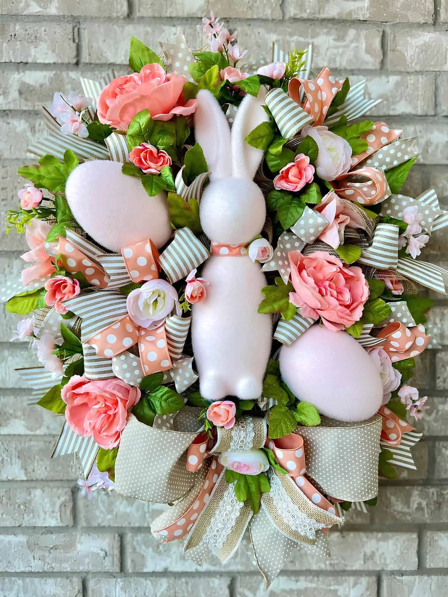 复活节门饰，配有织物兔子、花卉点缀和条纹丝带