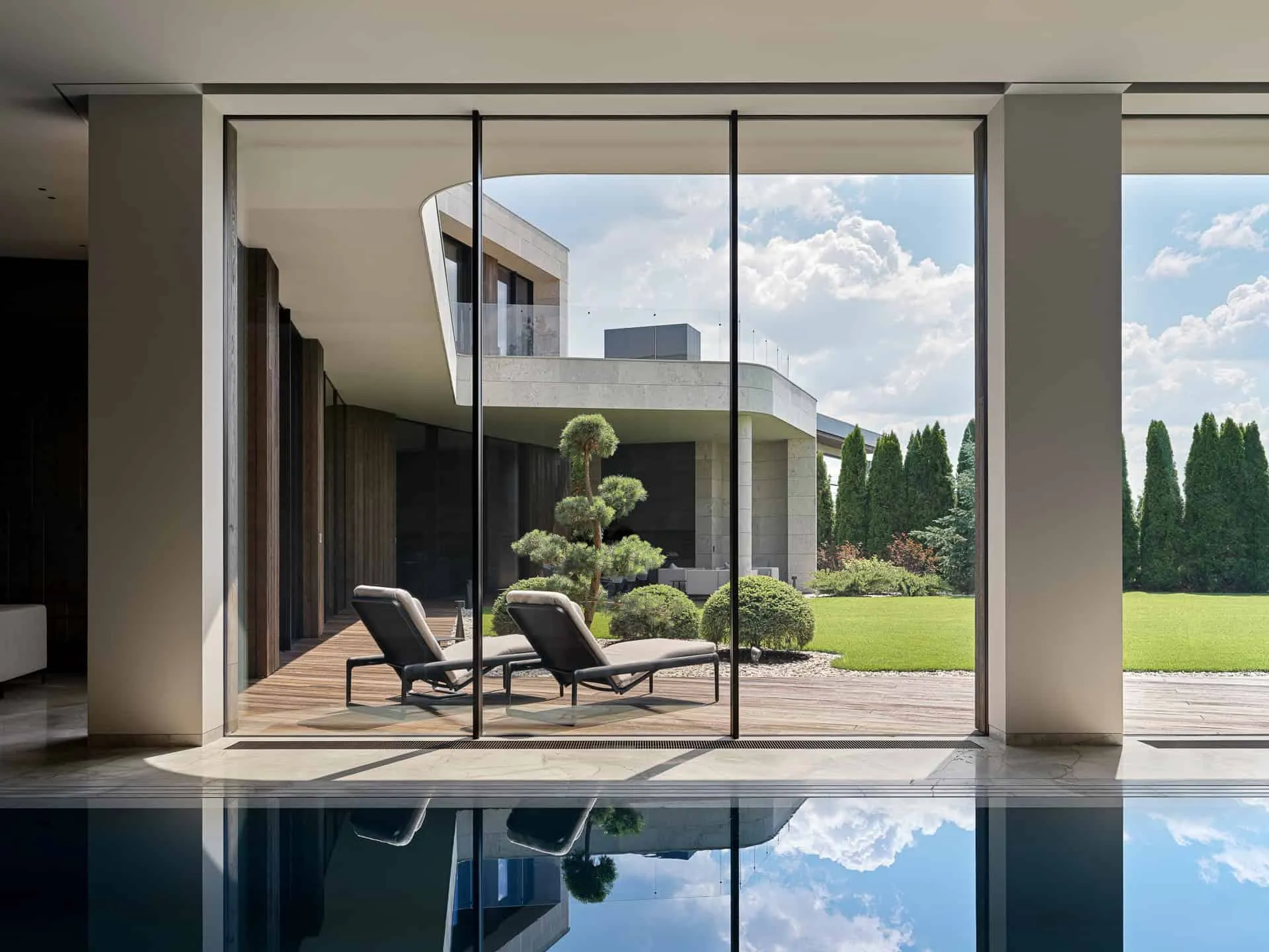玻璃门通往花园的泳池区域前方两个躺椅。