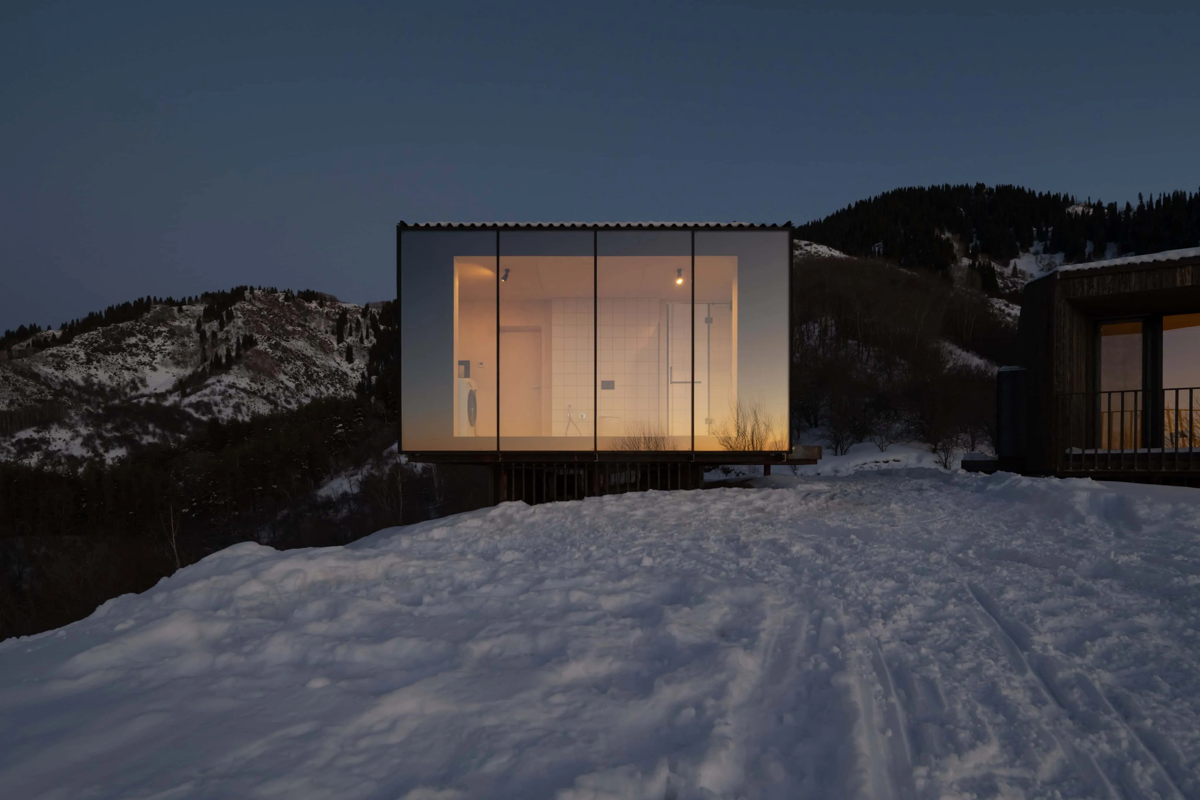 阿姆小屋玻璃立面展示柔和照明的极简浴室内饰。