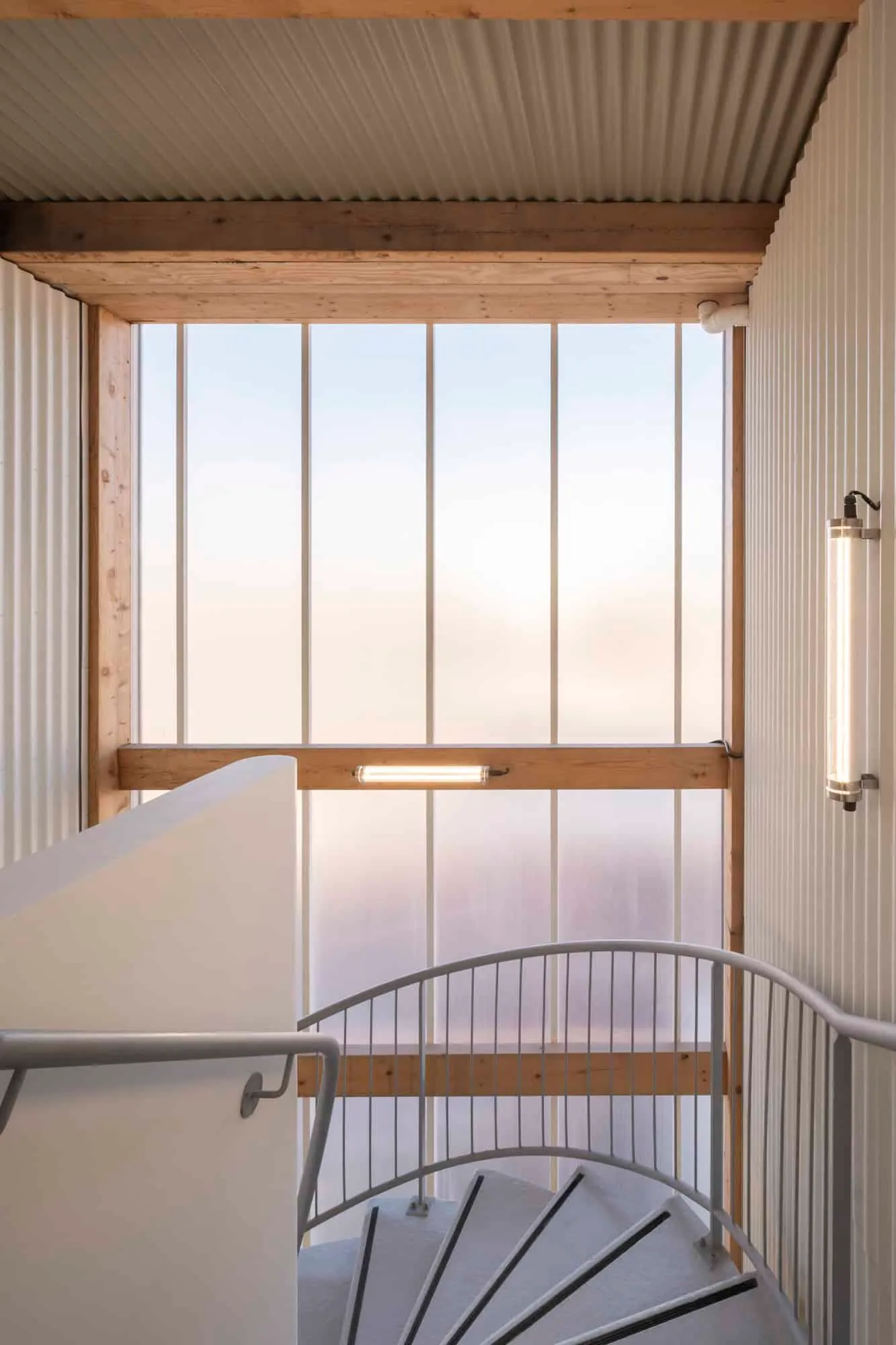 Internal spiral staircase near a semi-transparent façade panel