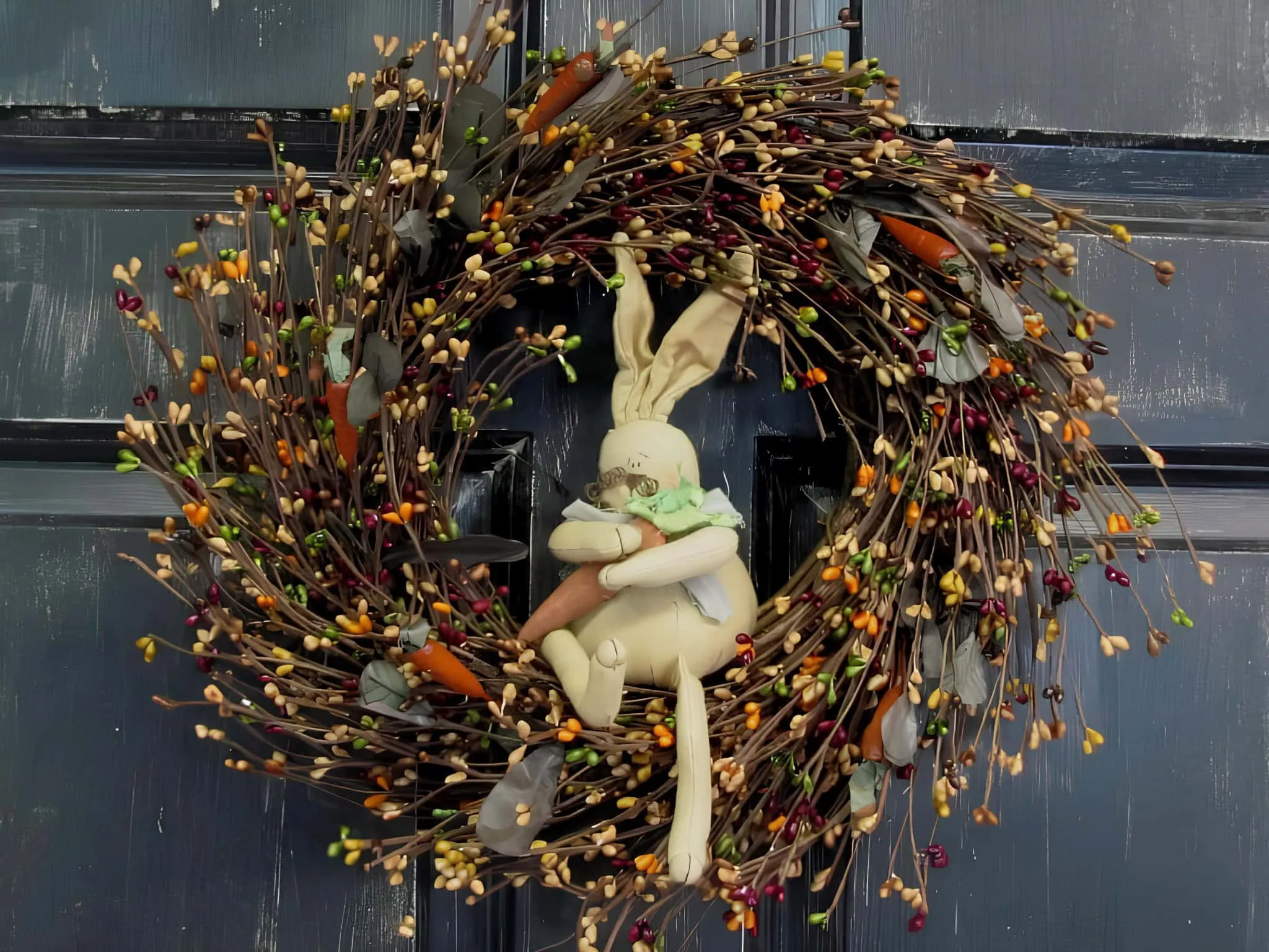 复活节门饰，配有鲜艳浆果和坐着的毛绒兔子