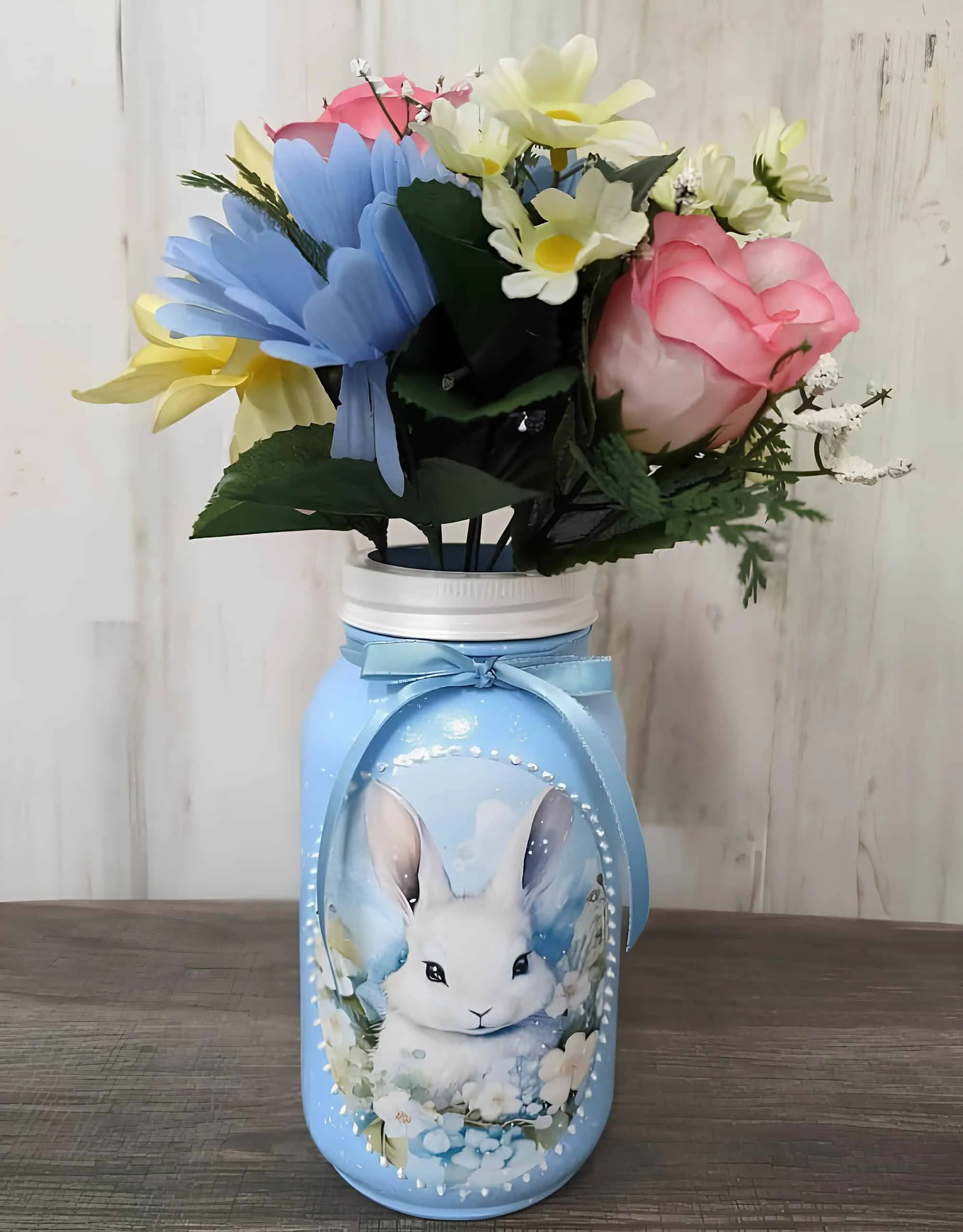 粉蓝色 Mason 罐子，涂有白色兔子图案并装有柔和春季花