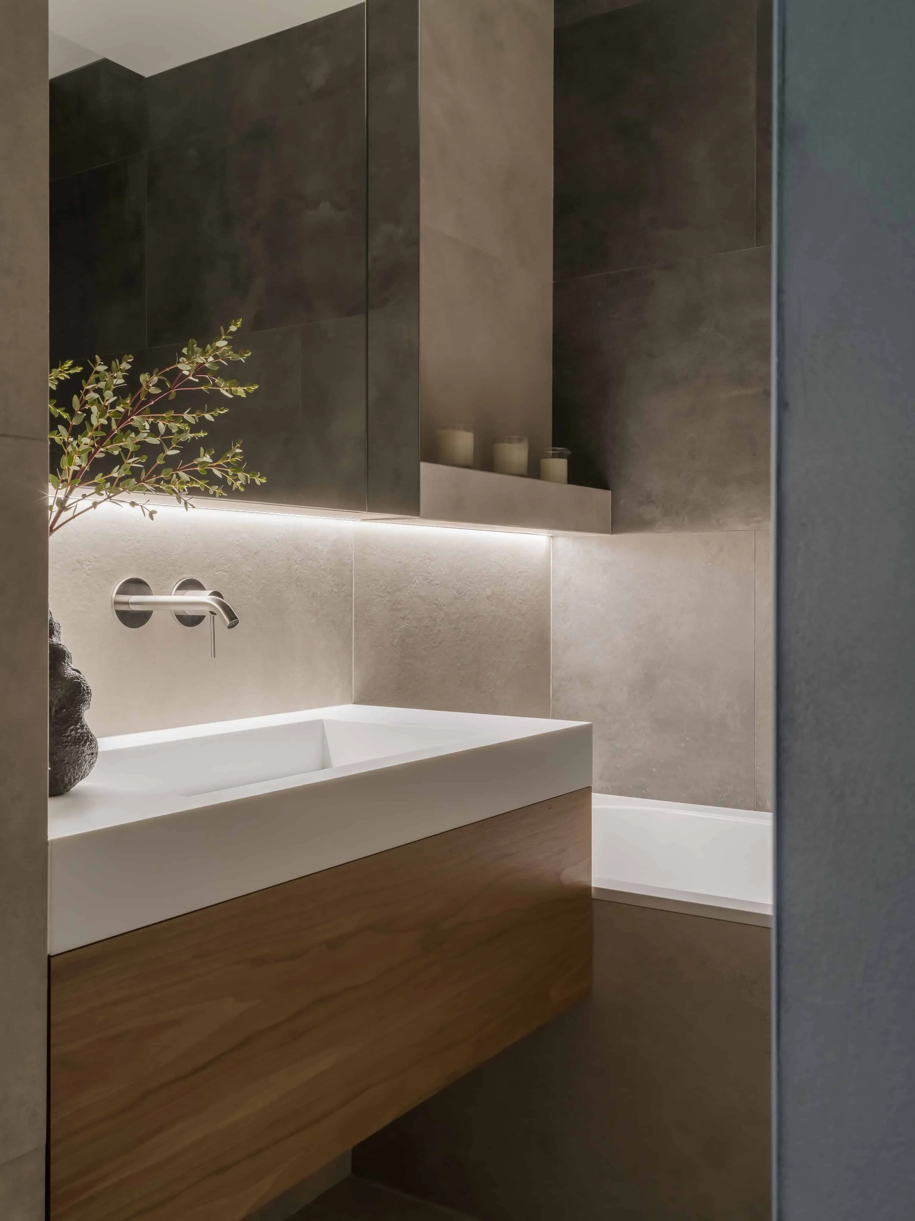 带照明的漂浮洗手台与深色瓷砖，营造优雅极简效果。