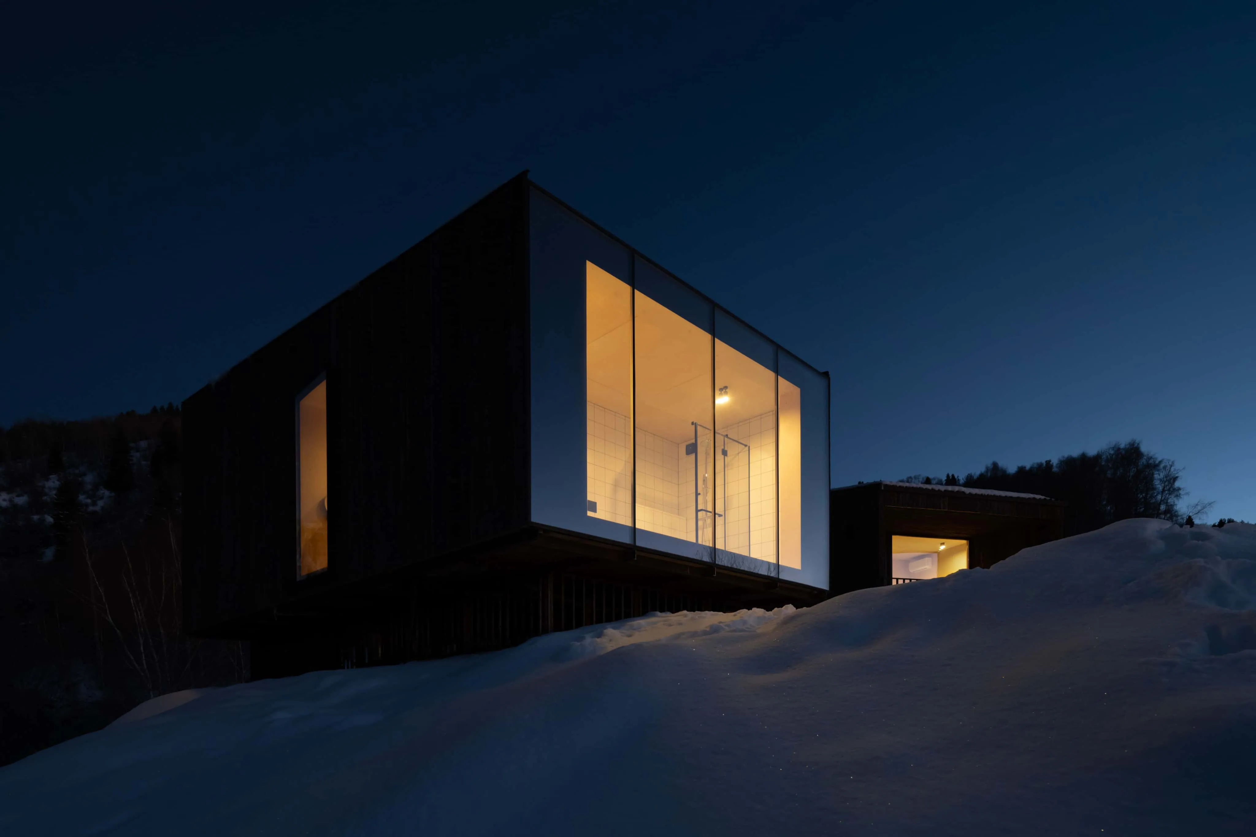 玻璃小屋内照明浴室，夜晚星空下的柔和光亮。