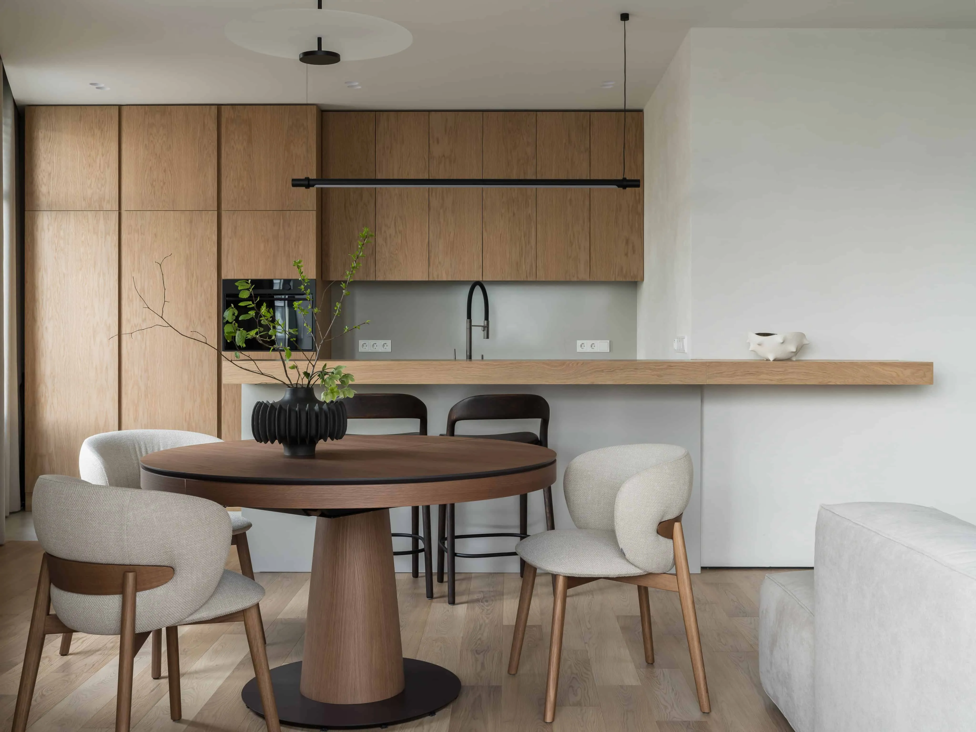 开放式厨房，配胡桃木橱柜、柔和照明与优雅现代餐桌家具。