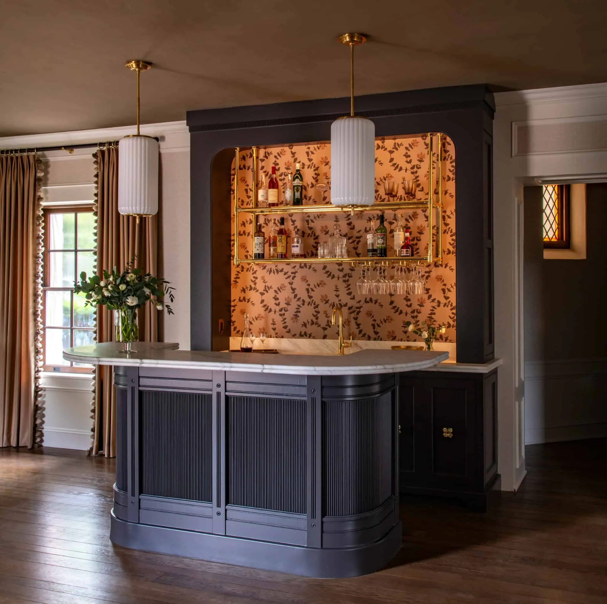 鲍尔长廊优雅的酒吧角落，配有金色搁板、花卉壁纸和深蓝色面板。