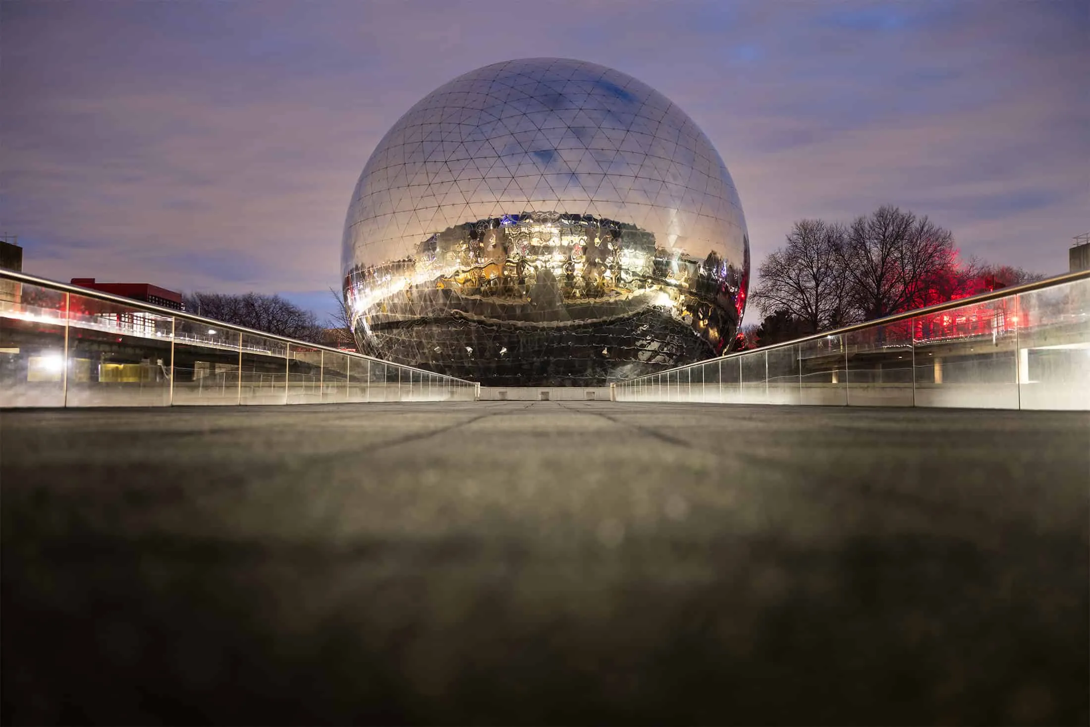 Night view of the reflective La Géode sphere in Paris, surrounded by soft celestial lighting.
