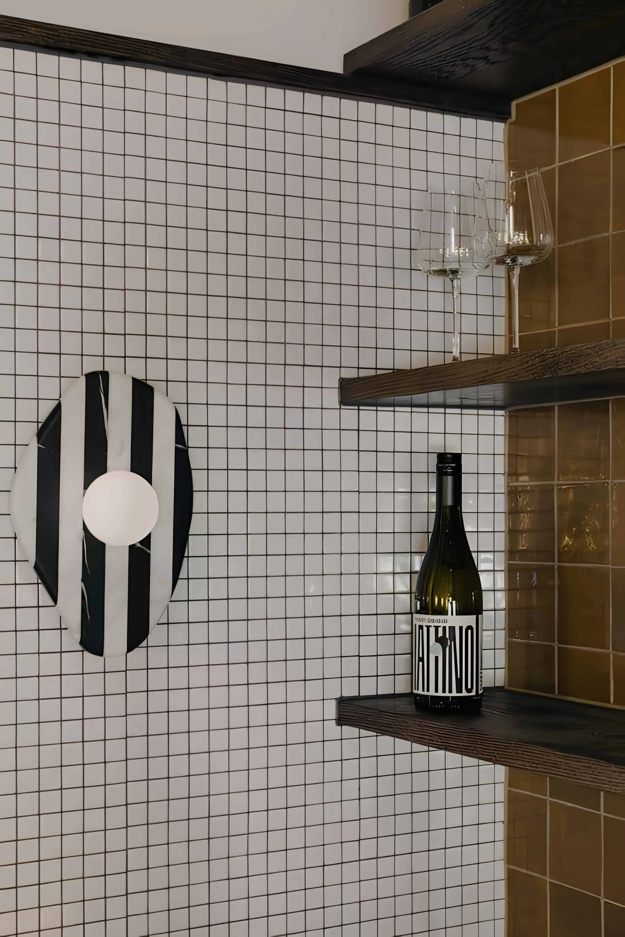 Black and white graphic wall light on tiled wall next to wine shelves