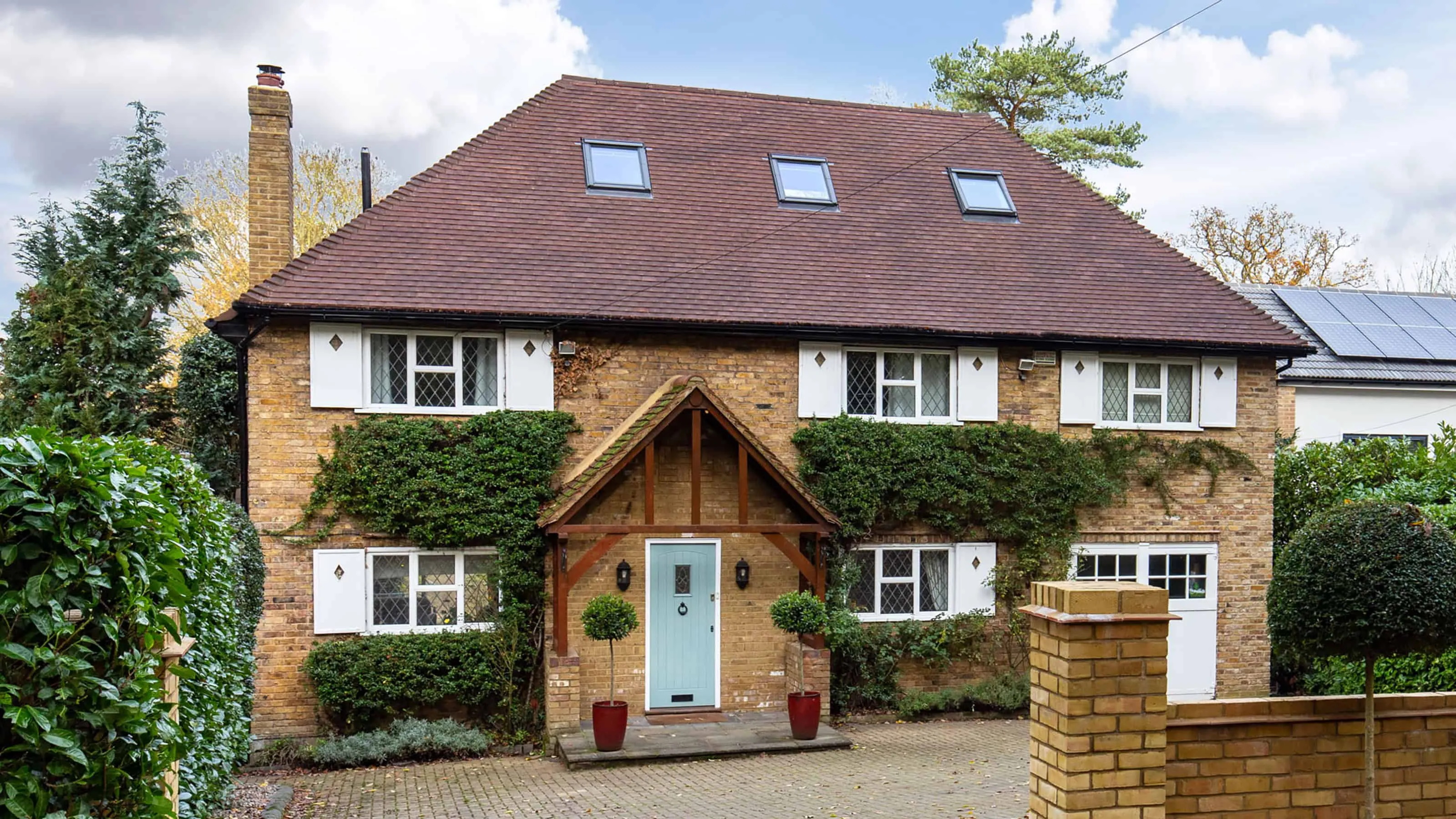 Traditional English house with a hip roof, brick exterior wall and symmetrical window arrangement